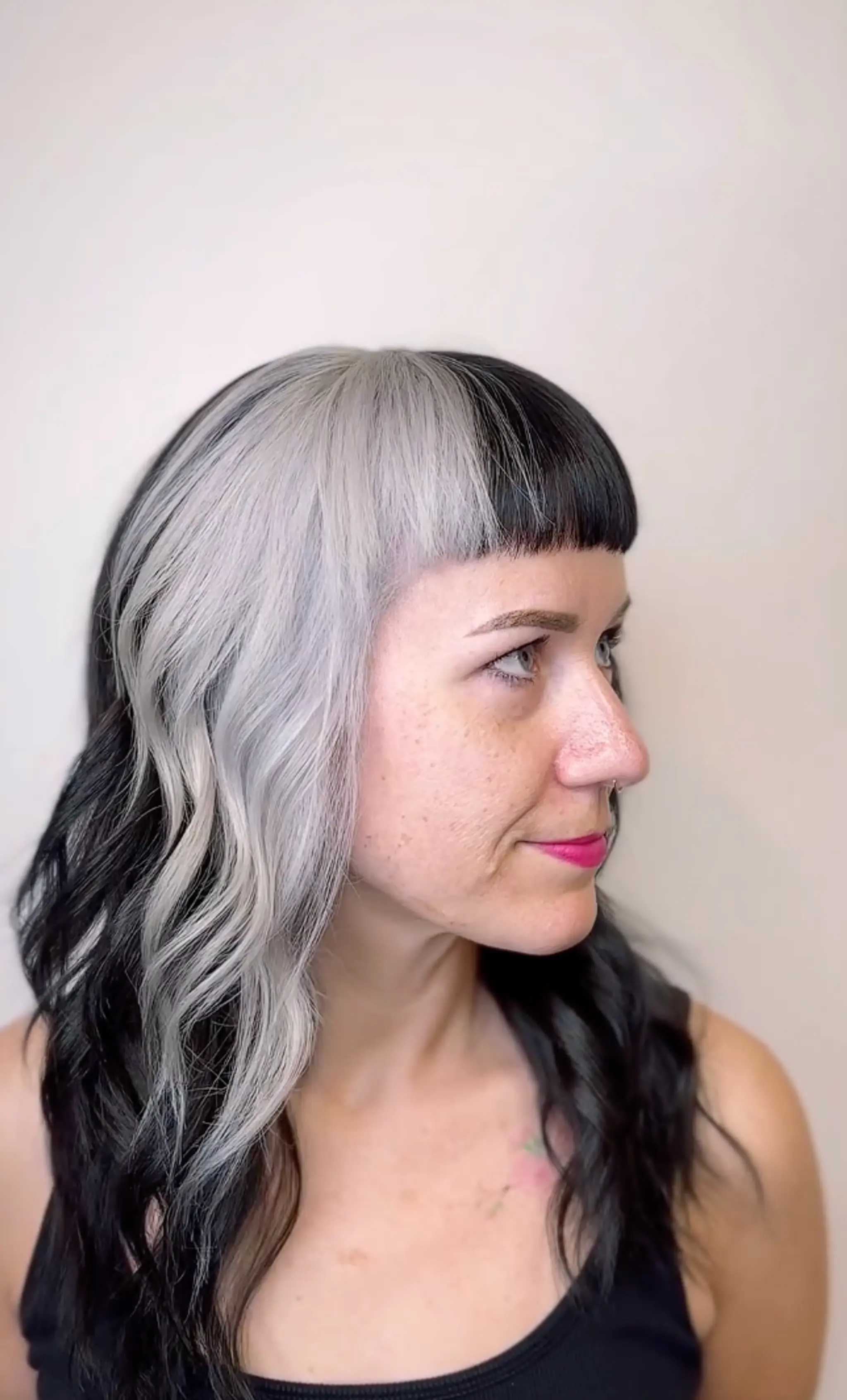 A striking two-tone color scheme with black and grey sections, medium length wavy hair, and blunt bangs providing a bold and edgy appeal.

Color by @simabeautynyc
Cut and style by @juliamannino_hair
 1