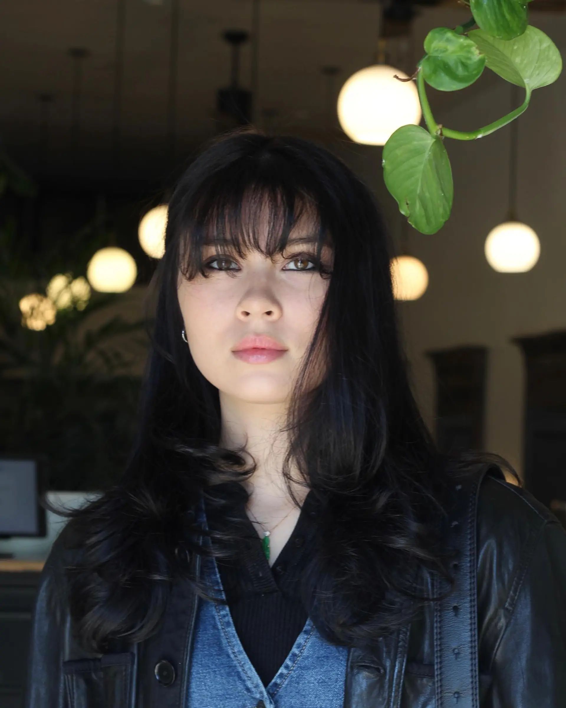 Long jet-black layered hair styled with soft, curved ends and eye-skimming wispy fringe bangs. 1