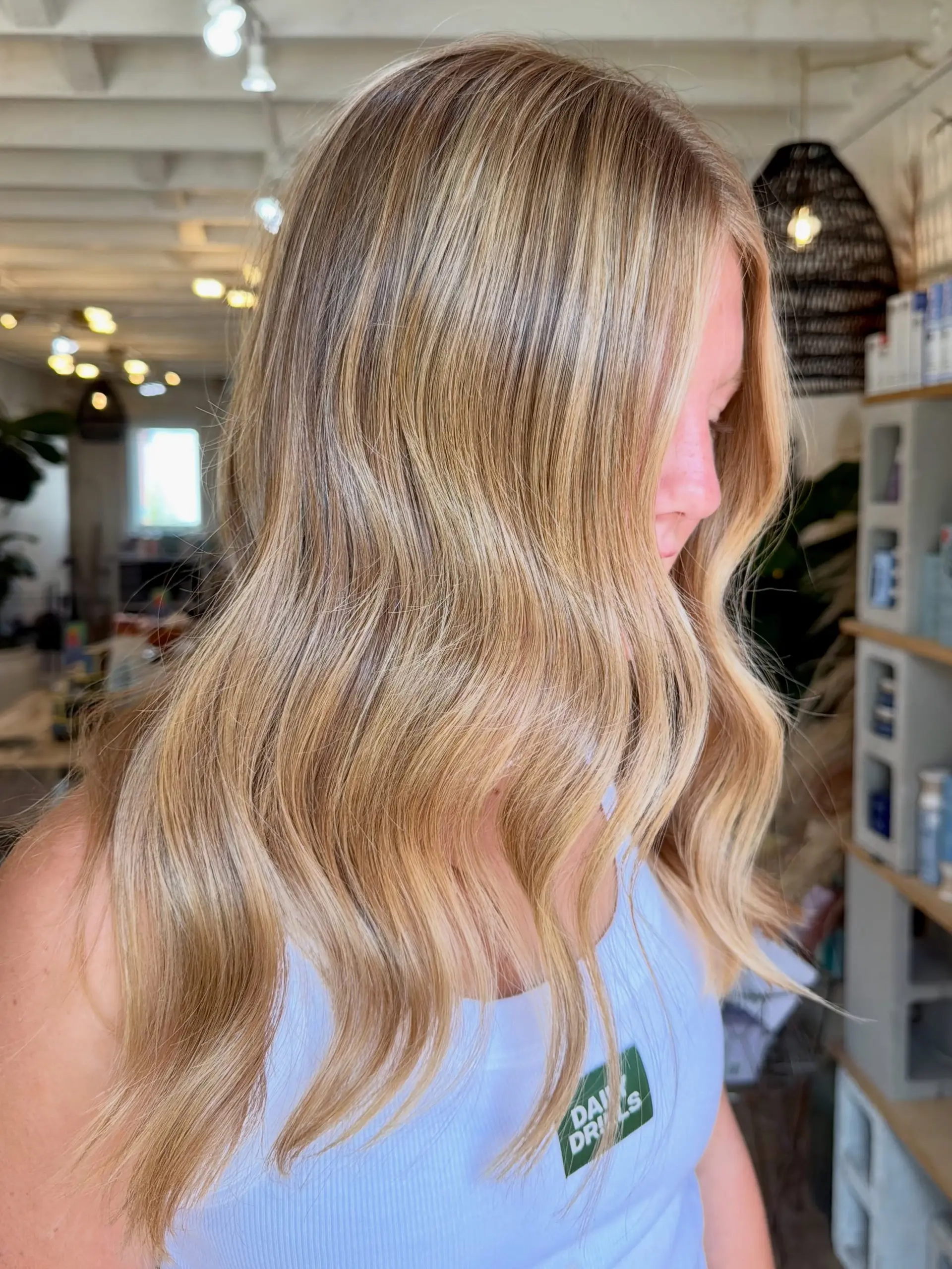 Long dimensional warm blonde hair styled in soft, loose waves. 1