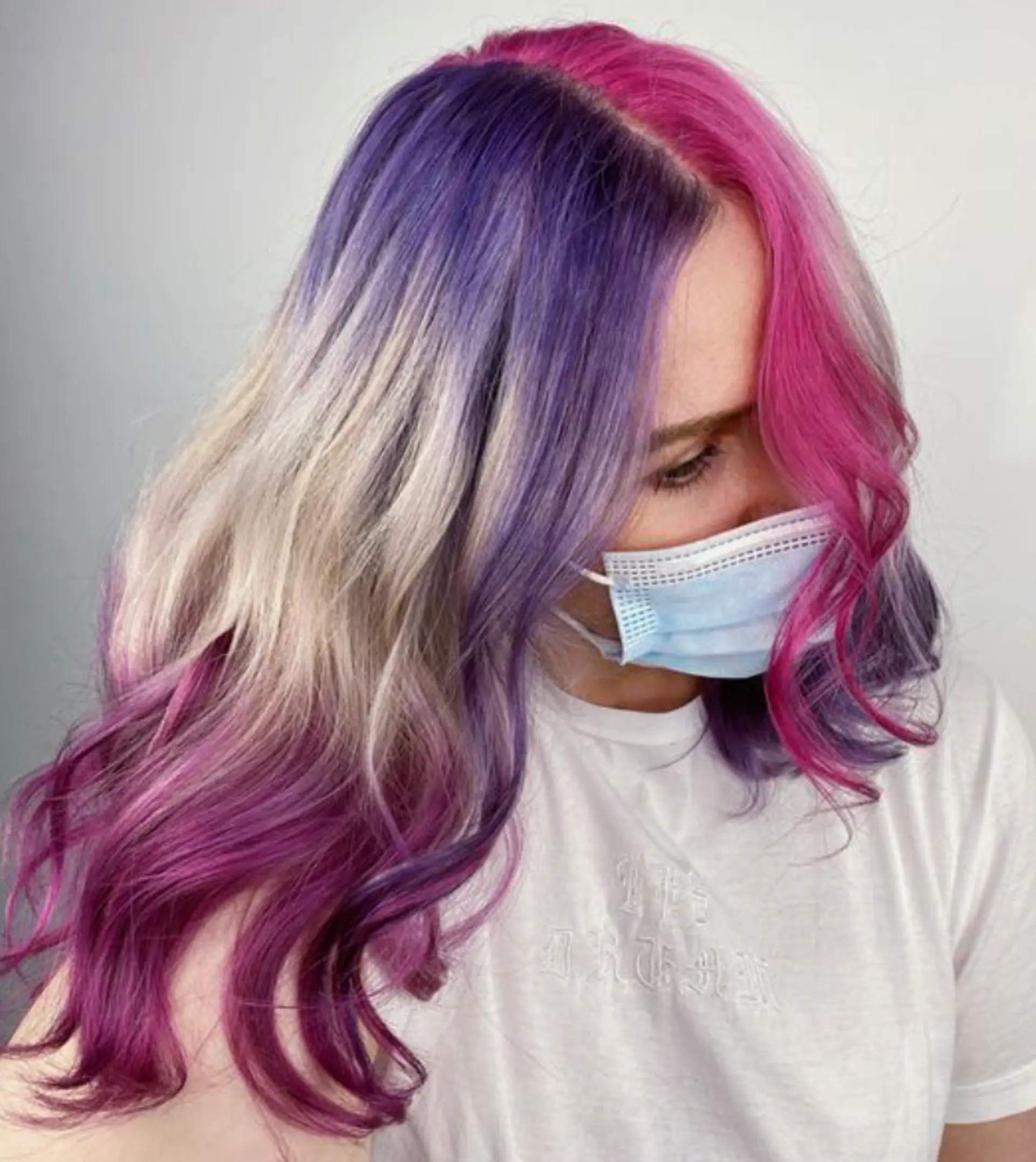 This wavy, medium-length hairstyle features a stunning rainbow cascade of pink, blonde, and purple hues. The vibrant waves create a playful, dynamic look. The layers add volume and movement to the hair, making it appear effortlessly stylish. 2