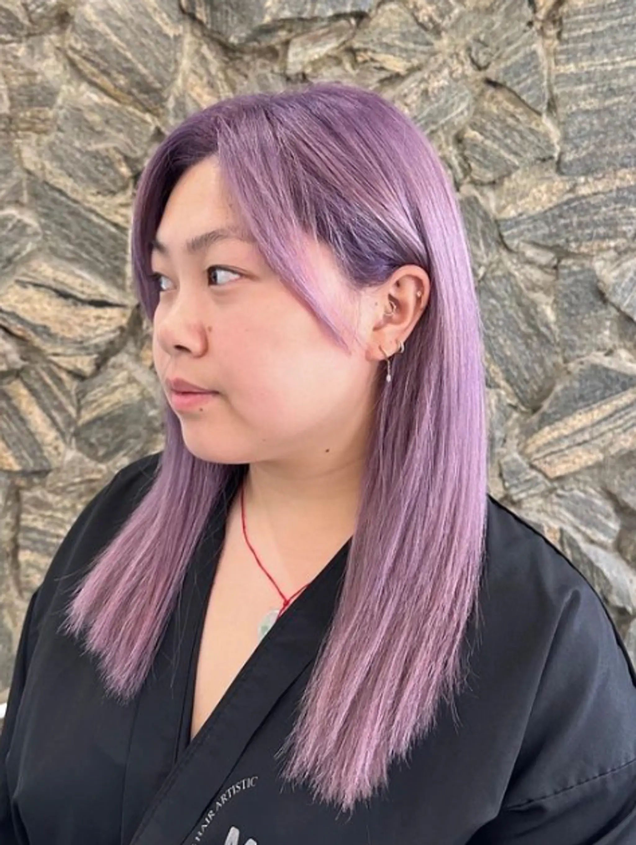Long, sleek straight hair dyed a vibrant lavender, parted in the center with sections tucked behind the ears. 1