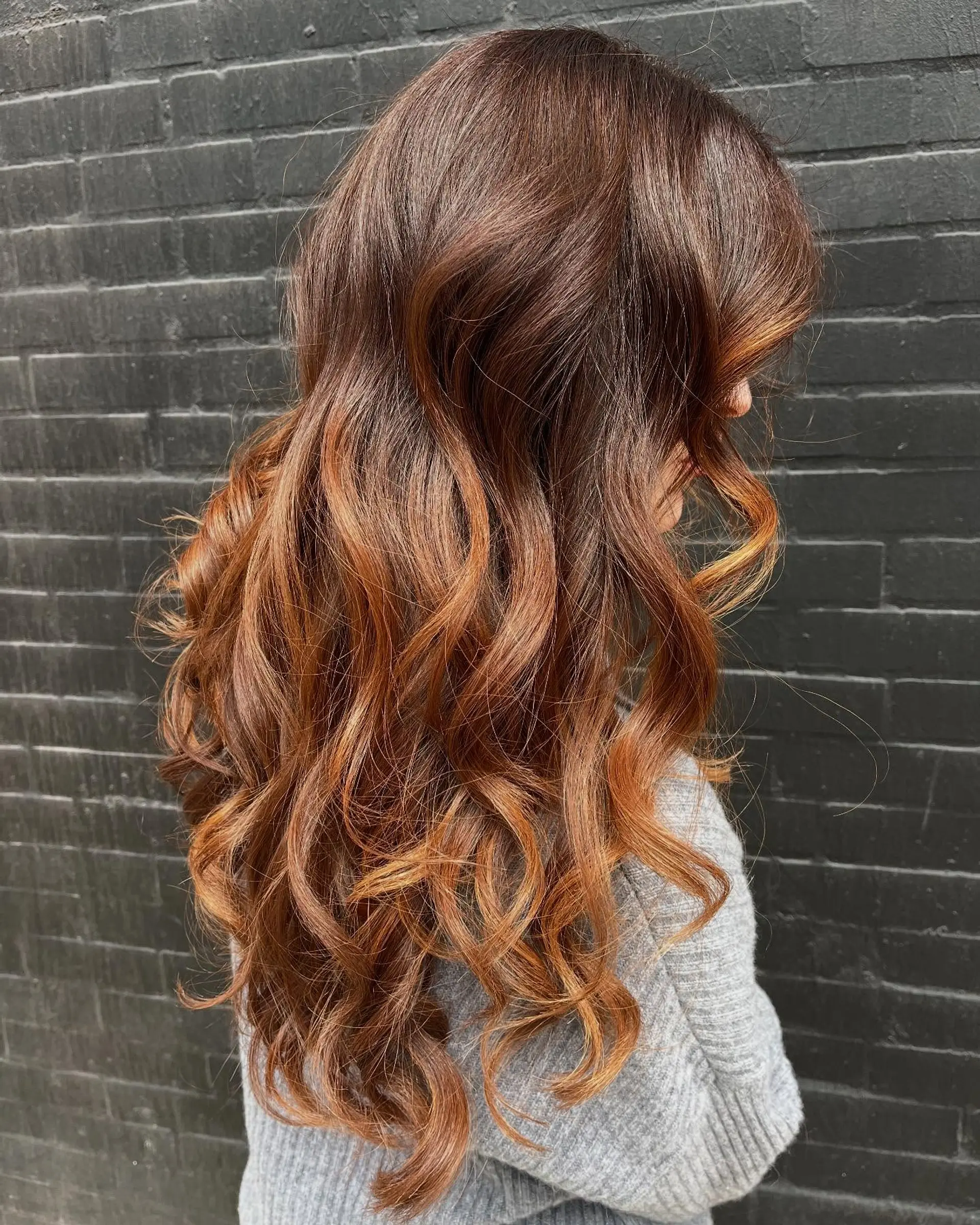 Glossy long auburn hair with warm copper balayage accents styled into soft, defined waves. 1