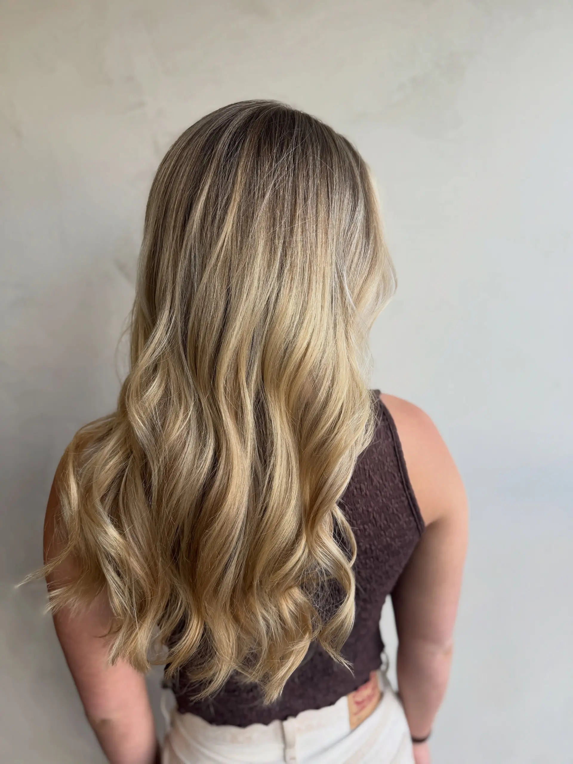 Long dimensional blonde hair styled into loose, elegant waves that emphasize natural dimension. 1