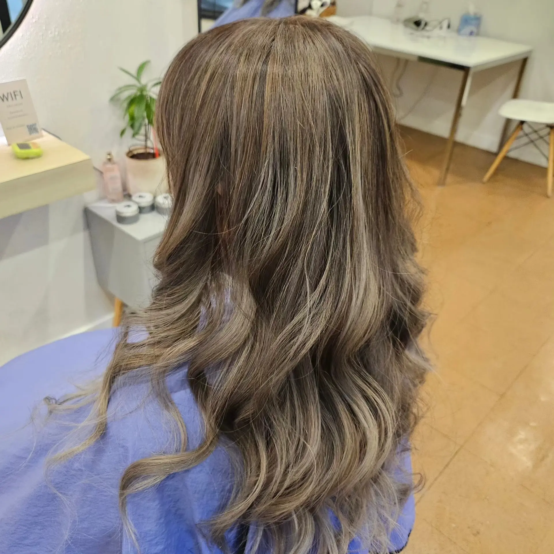 Long flowing hair styled in loose waves with a seamless cool ash balayage. 1
