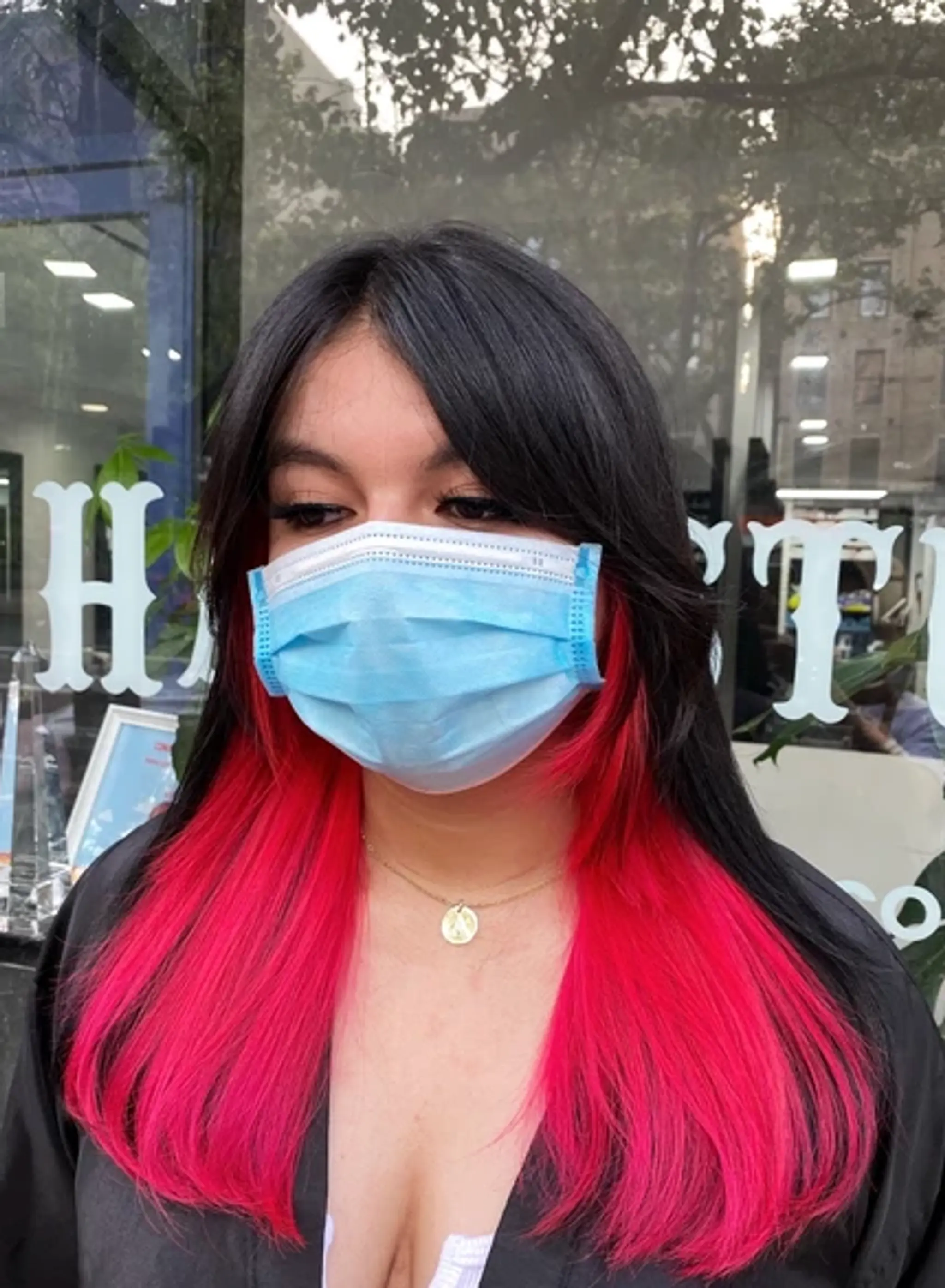Long, straight hair with a rich black base and vivid neon pink lower halves, creating a striking ombre effect. The hair features face-framing layers and subtle layering that enhances the overall movement and dimension.