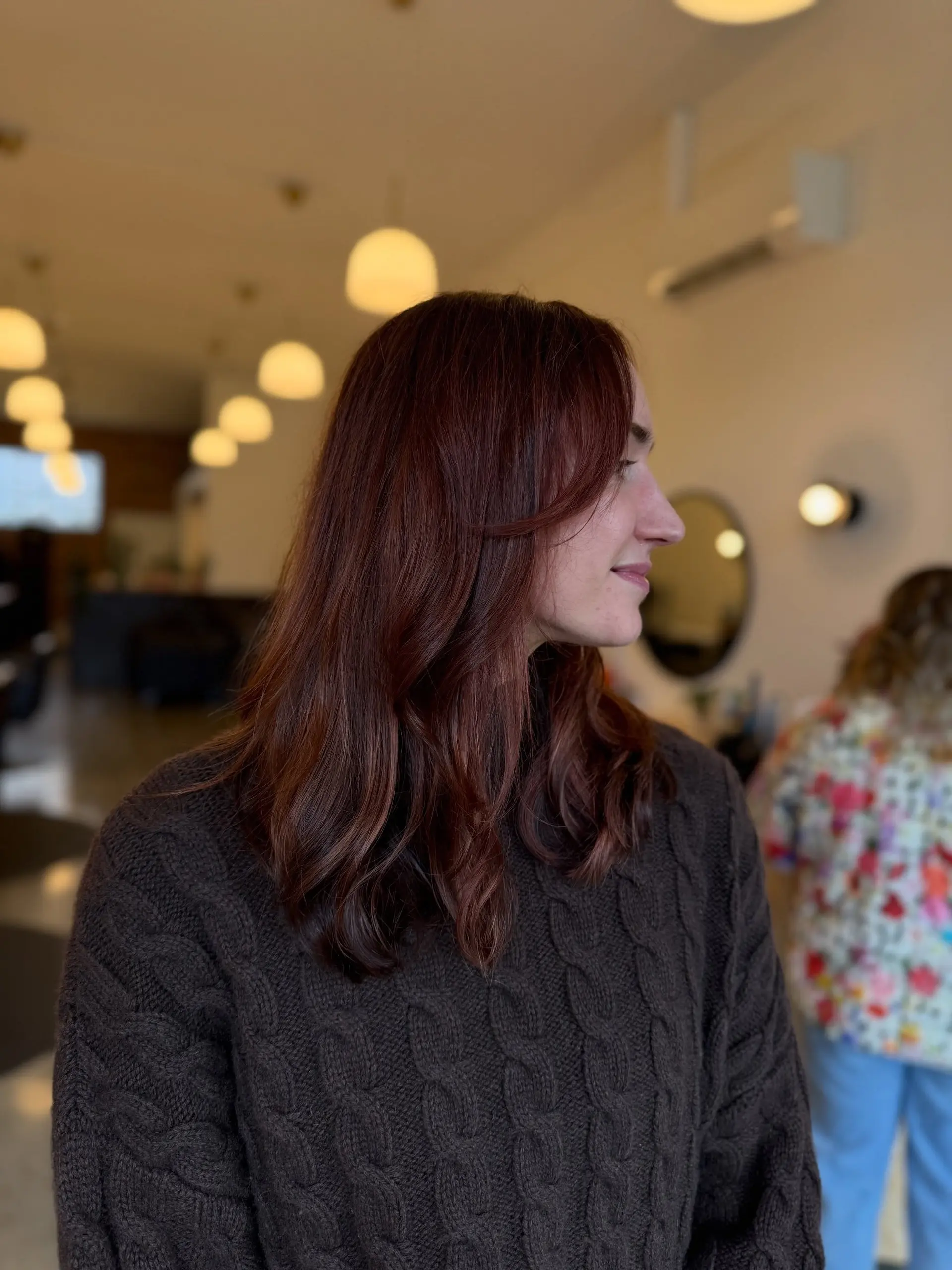 Medium-length deep auburn mahogany hair with gentle face-framing layers and soft styling waves. 1