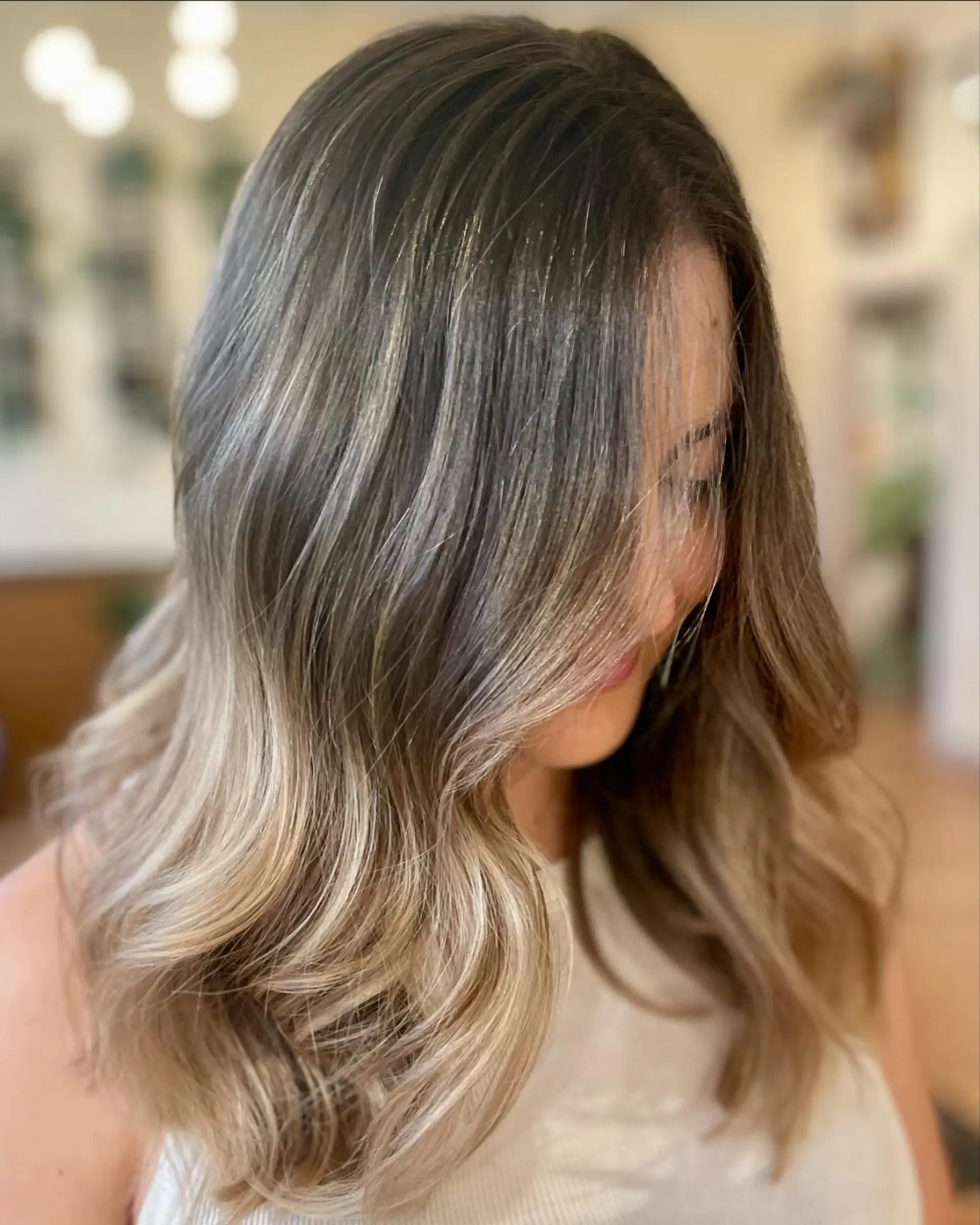 Long dimensional hair with fine blonde babylights, styled in soft voluminous waves with face-framing layers. 1