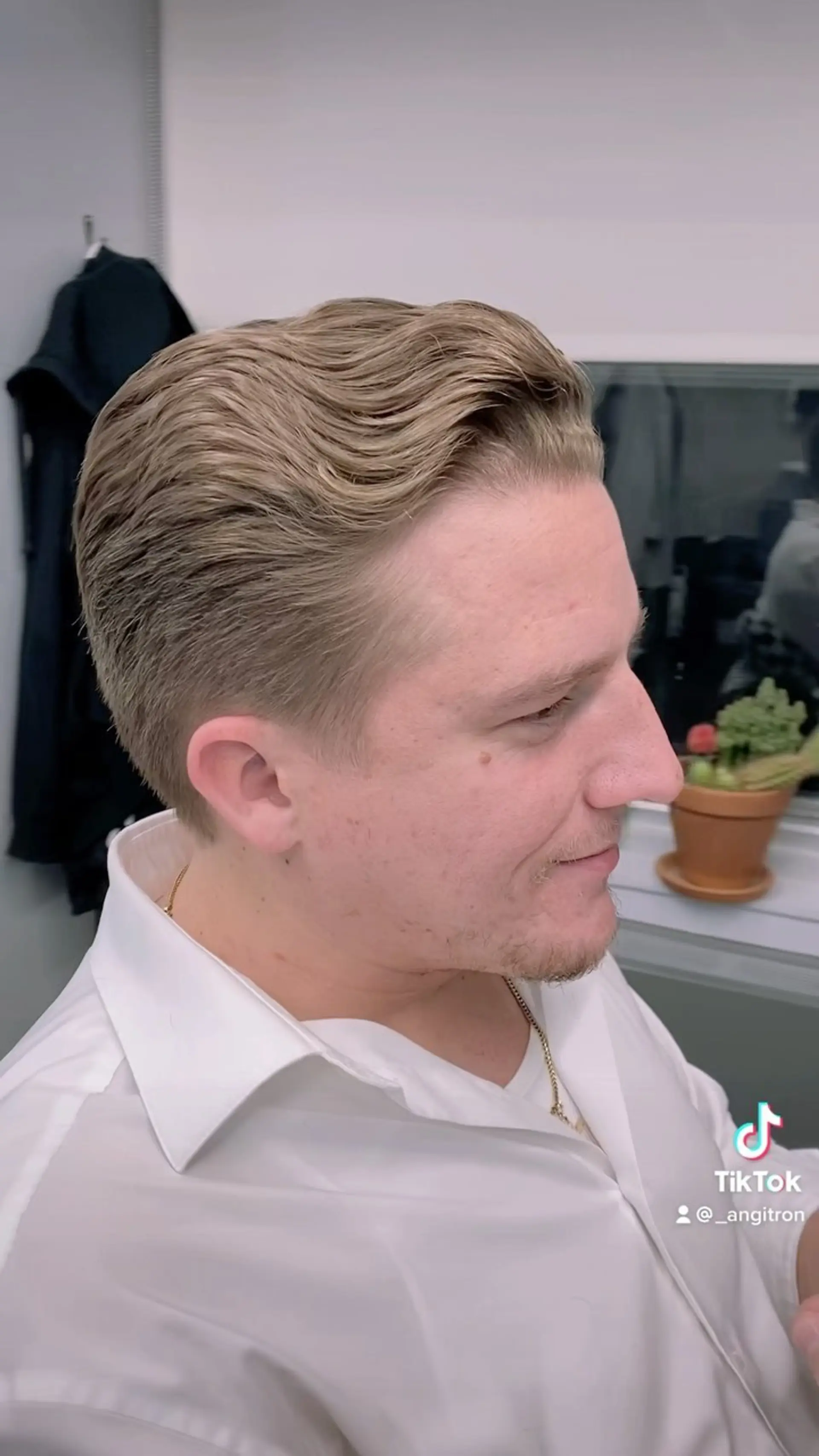 A short, classic haircut styled with textured waves swept back from the forehead and neatly tapered sides. 1