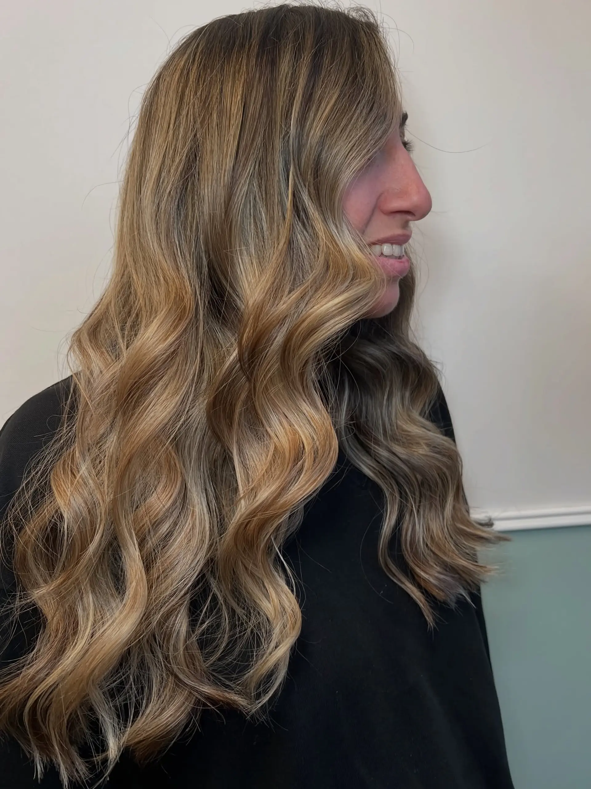 Long cascading waves featuring a seamless warm blonde balayage over a natural light brown base. 1