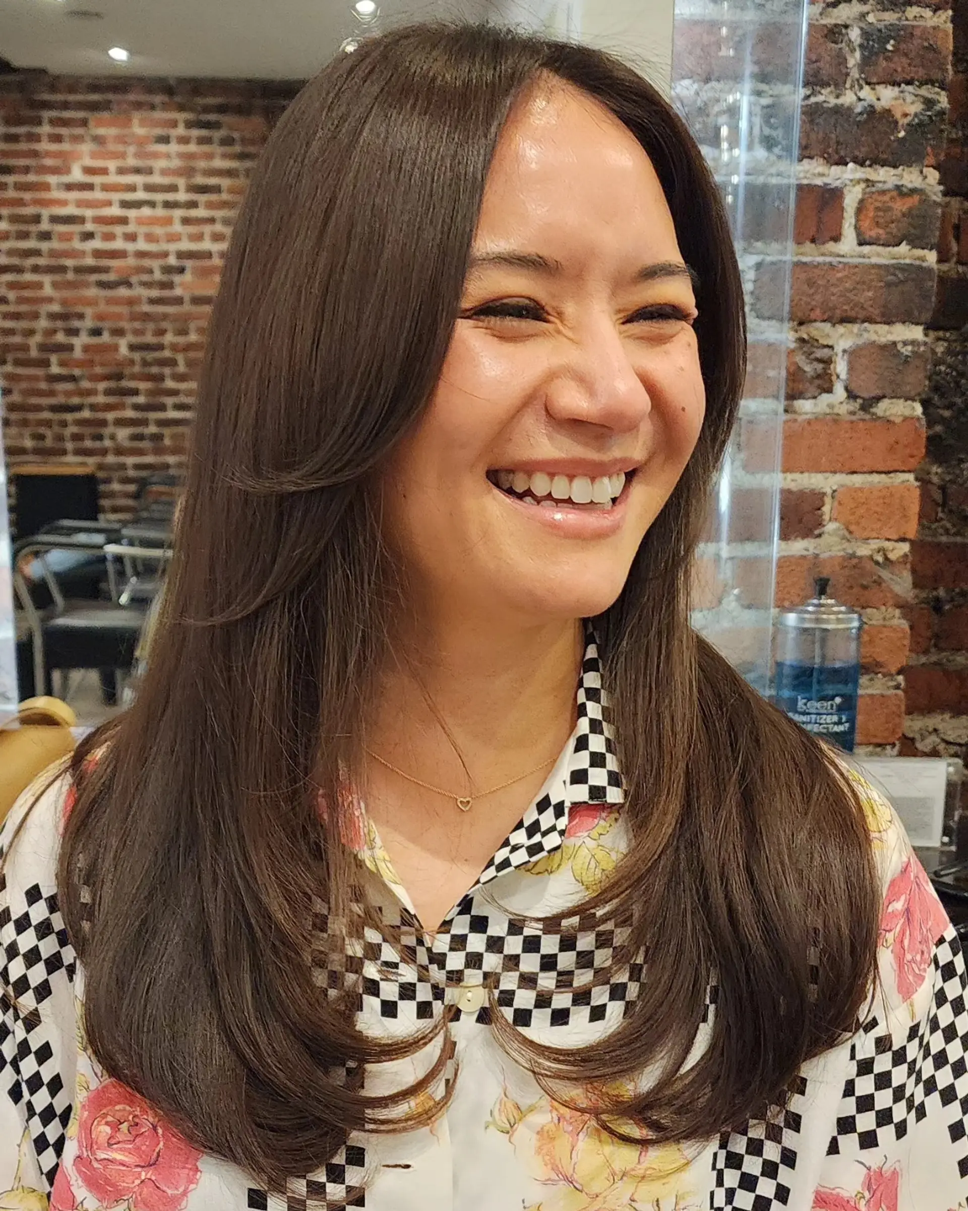 Long dark brown hair styled with smooth face-framing curtain bangs and bouncy layered ends. 1