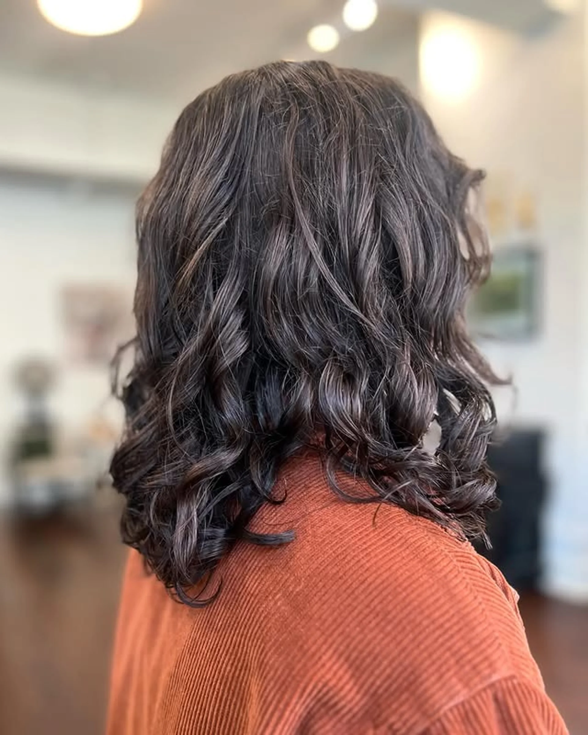 A person with a stylish medium-length wavy hairstyle in a rich auburn color, cut to shoulder length. - Preview 3