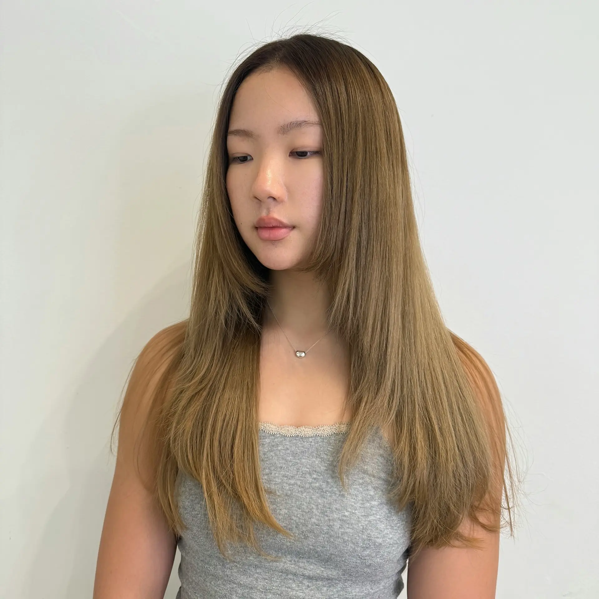 Long, sleek straight hair dyed in a soft caramel blonde shade with chin-length face-framing layers. 1