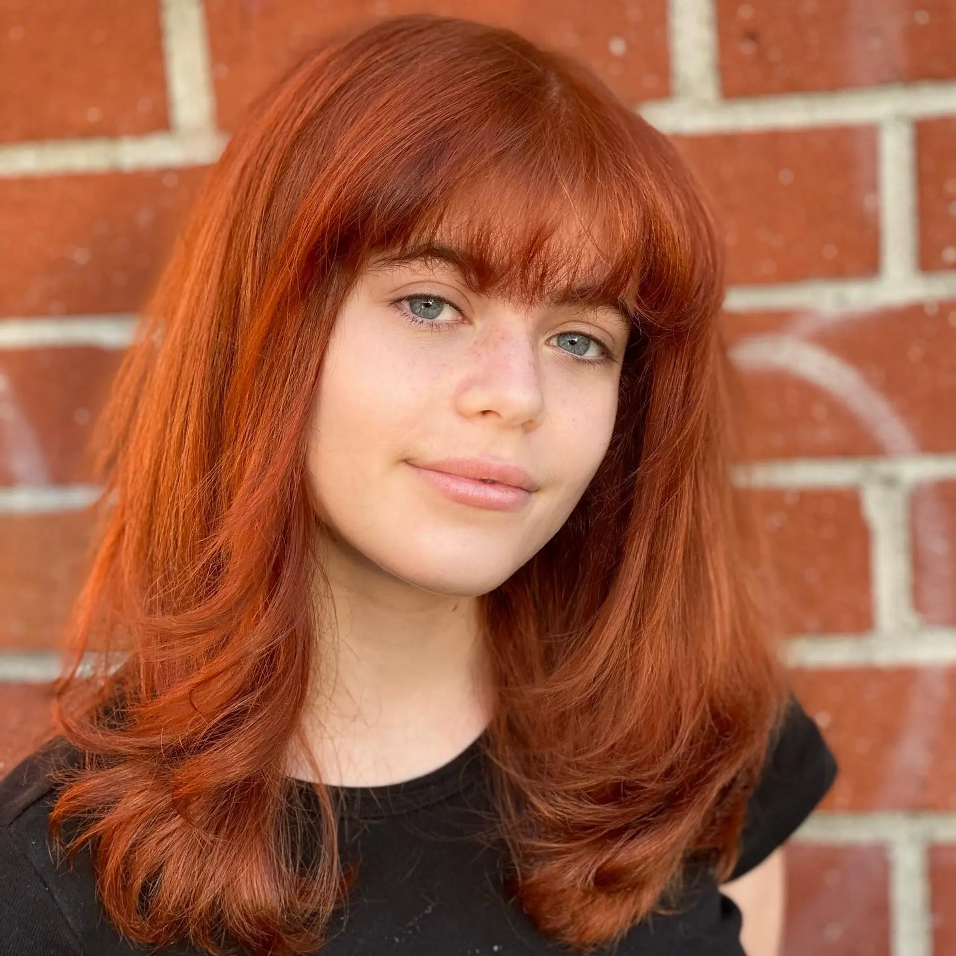 Medium-length rich copper hair styled with soft interior layers, a rounded blowout, and a textured full fringe. 1