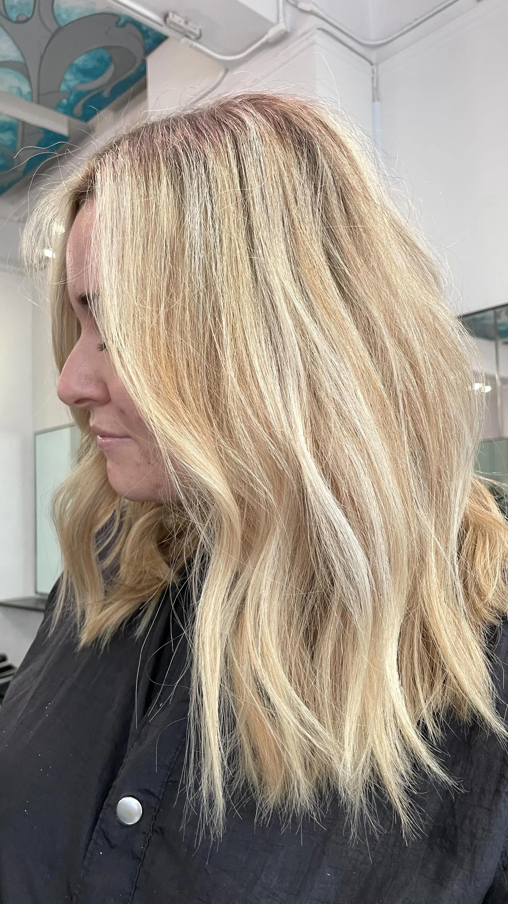 Medium-length layered blonde hair styled with soft lived-in waves and bright dimensional highlights. 1