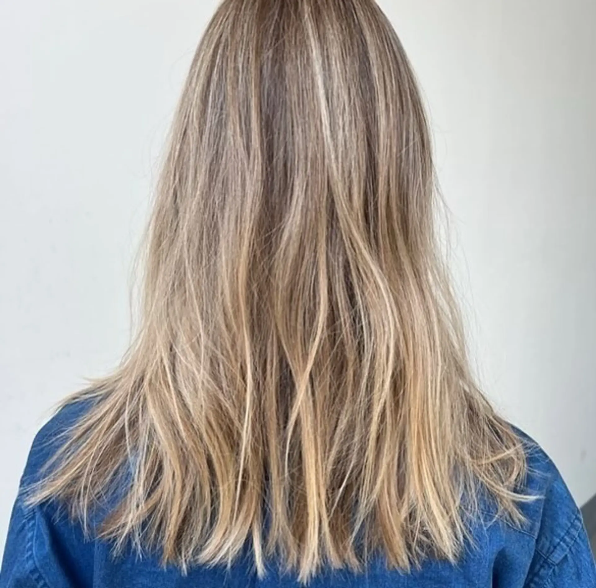 Medium-to-long layered hair featuring dimensional blonde highlights over a light brown base, styled with textured, piecey ends. 1