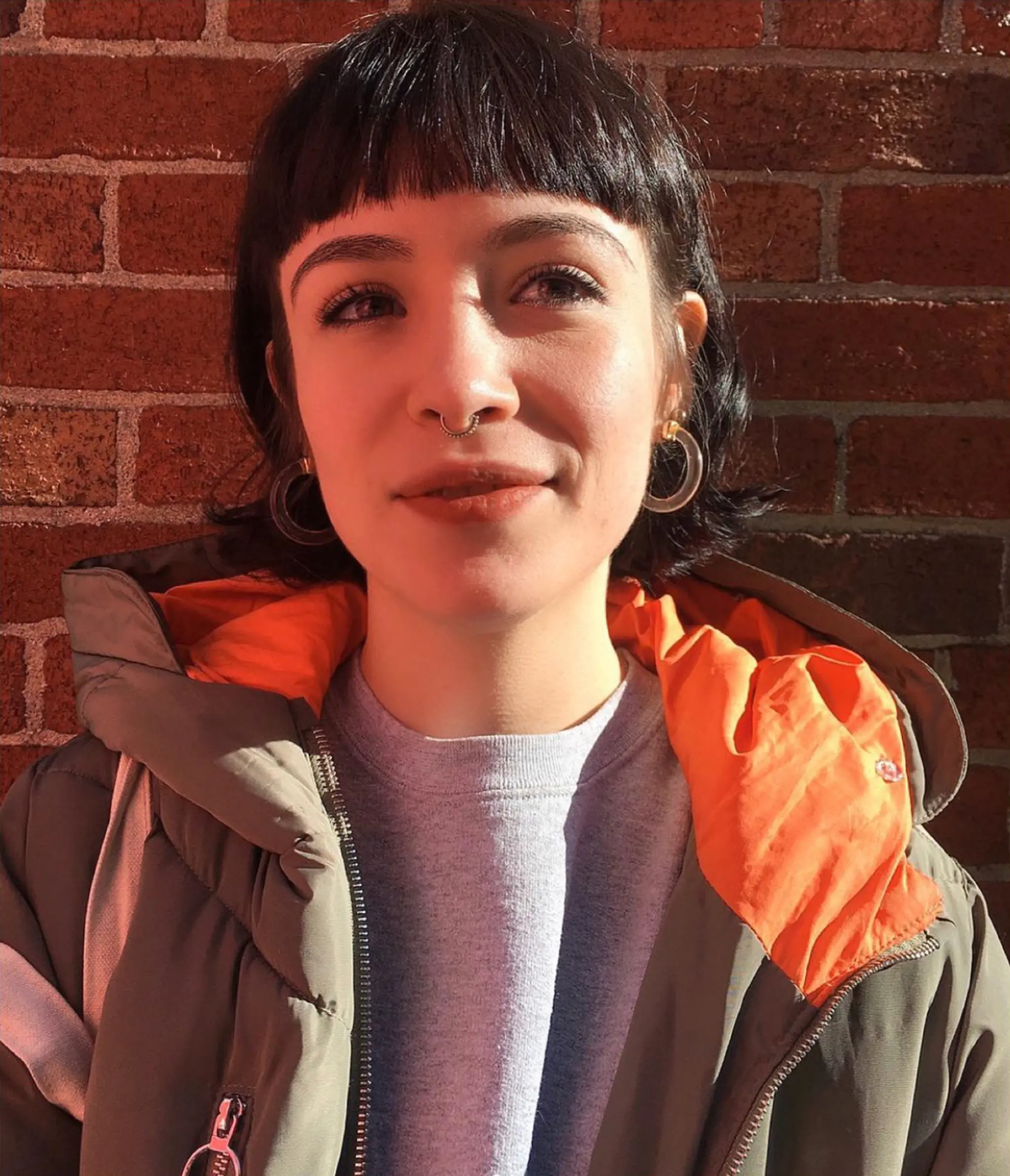 A stylish short bob with wavy texture and black color, featuring a blunt fringe that falls just above the eyebrows. Softly layered waves add volume and movement, creating a playful yet sophisticated look by Coco.