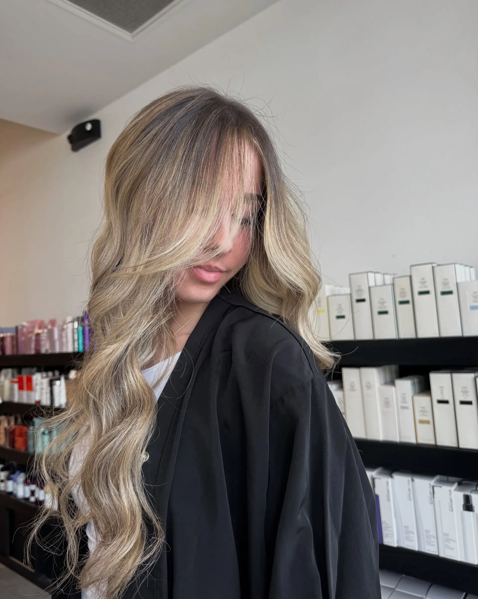 Long dimensional bronde hair styled with soft, loose waves and face-framing layers. 1