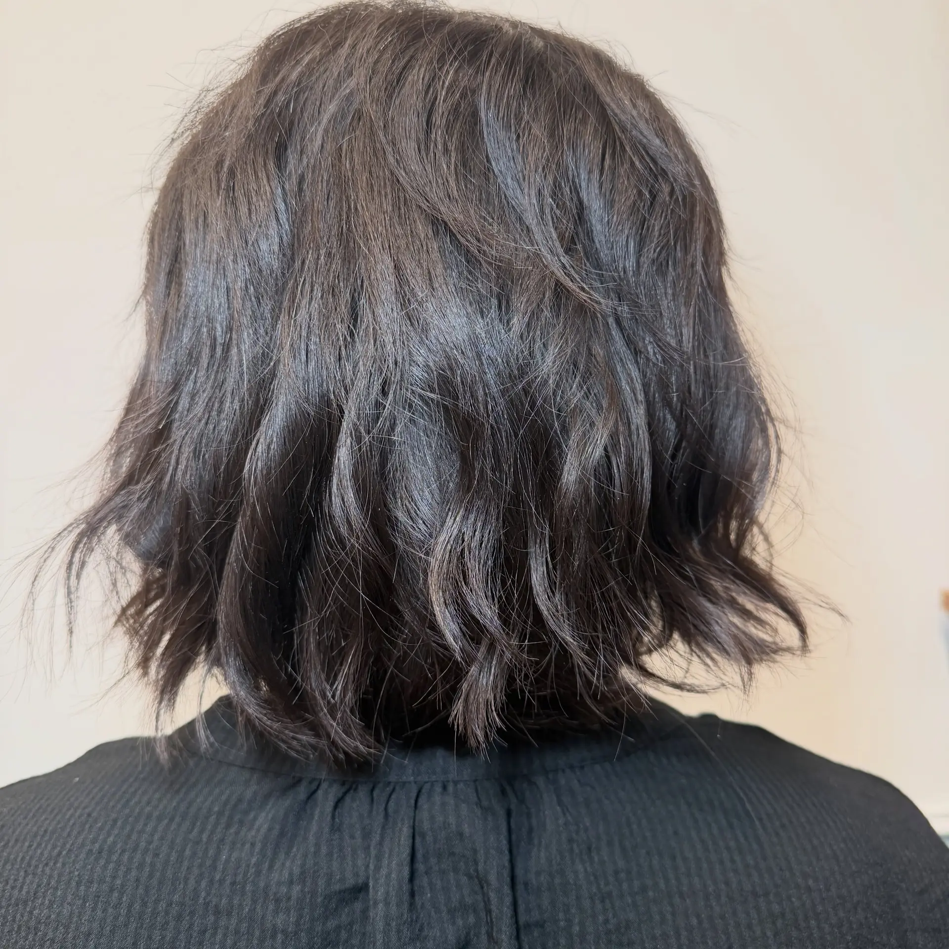 A textured dark bob haircut with soft tousled waves and piecey ends resting around the nape. 1