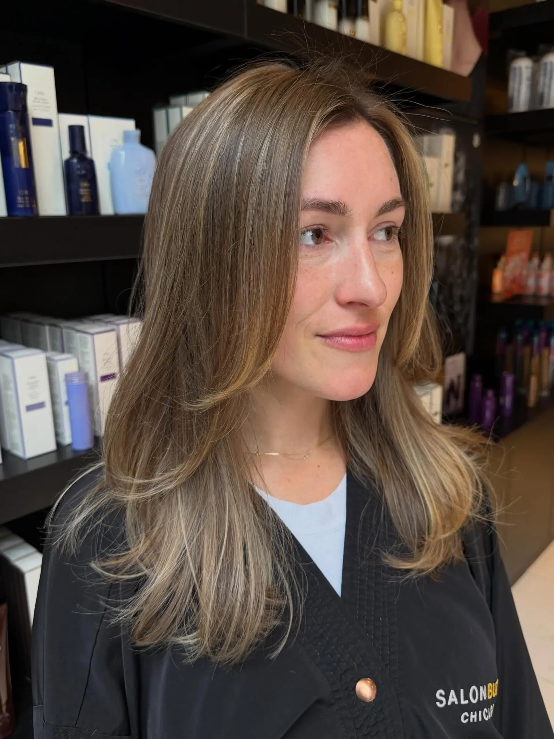 Long bronde hair featuring soft, blended ribbon balayage highlights with face-framing layers styled in a sleek blowout. 1