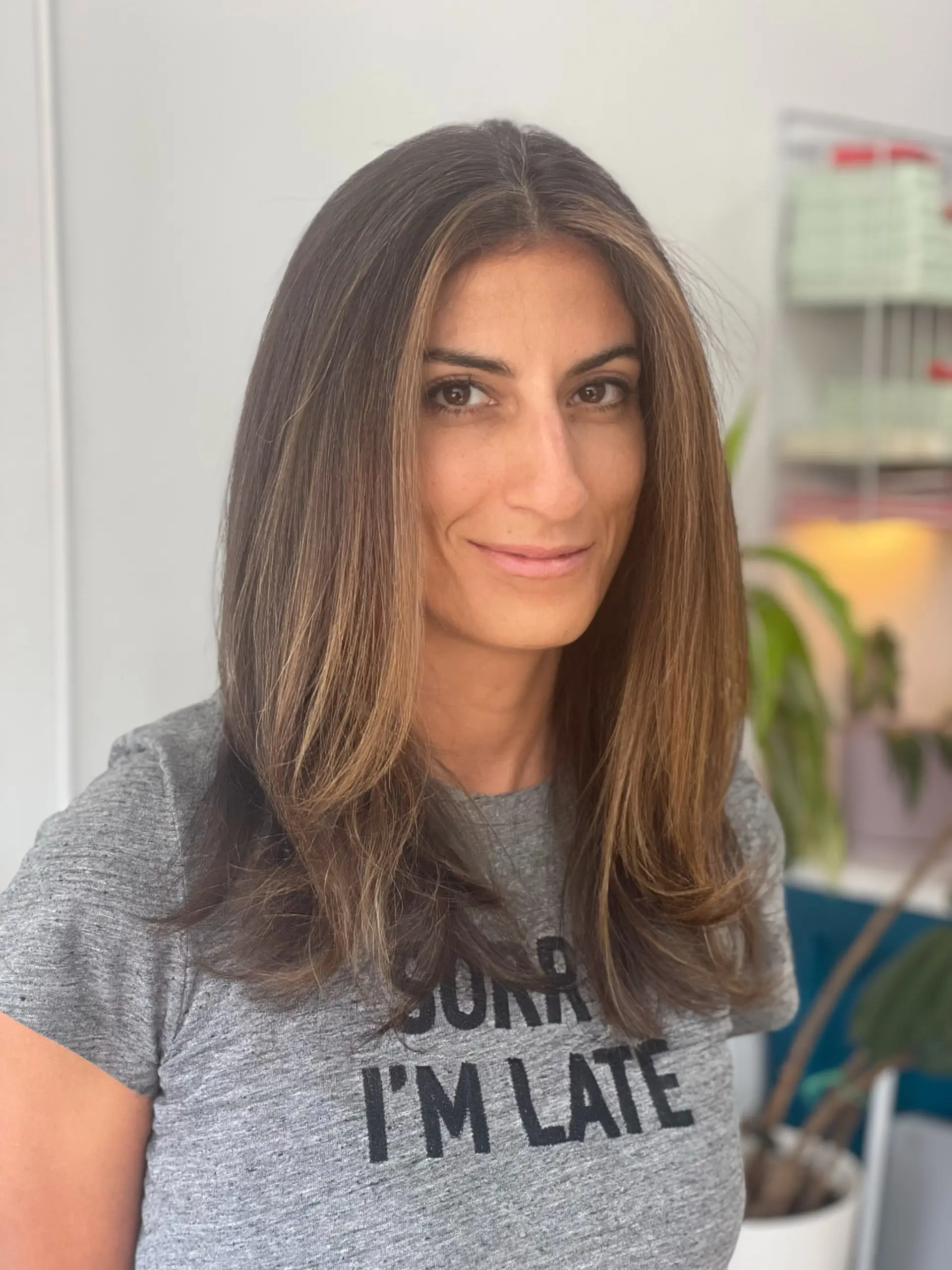 Long smooth brunette layers accented with bright, warm caramel face-framing highlights and softly turned-in ends. 1