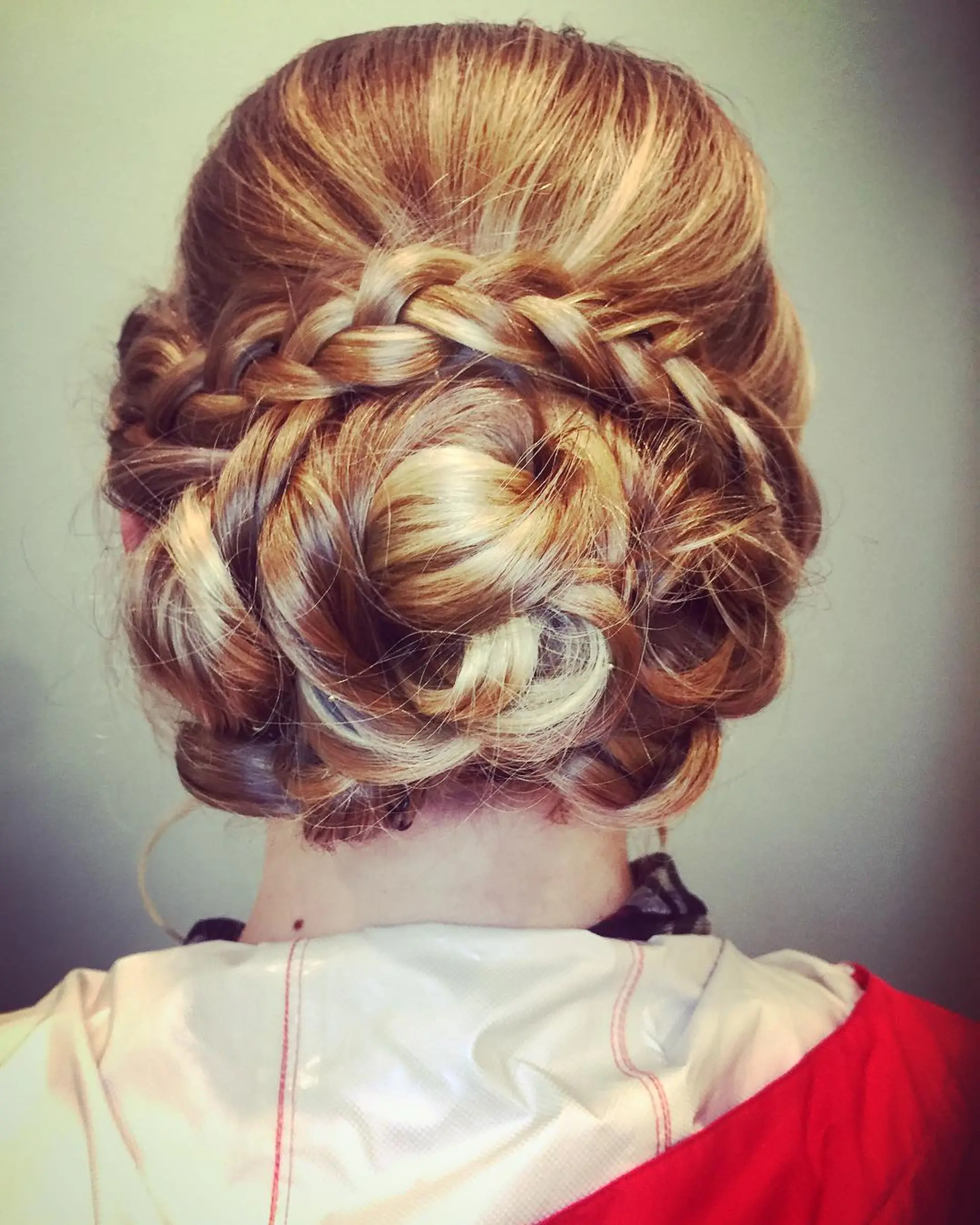 An intricate formal updo featuring a horizontal braid framing a soft, textured low bun. 1