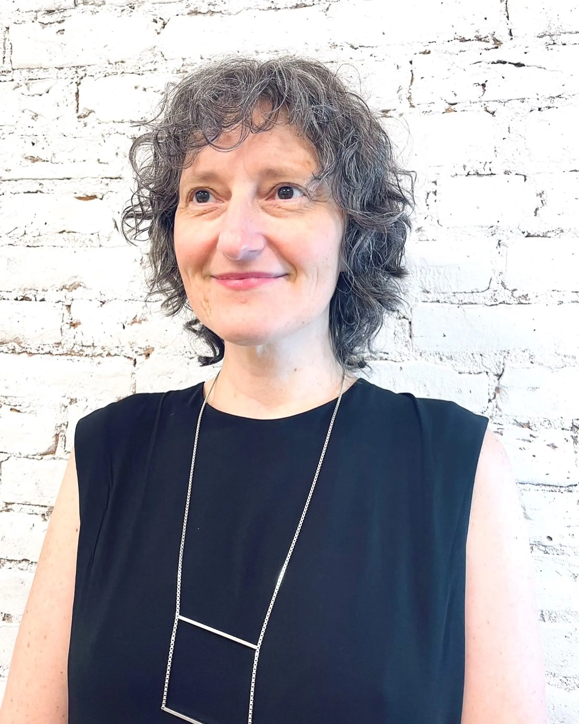 A short, naturally curly haircut with soft layers and wispy curly bangs. 1