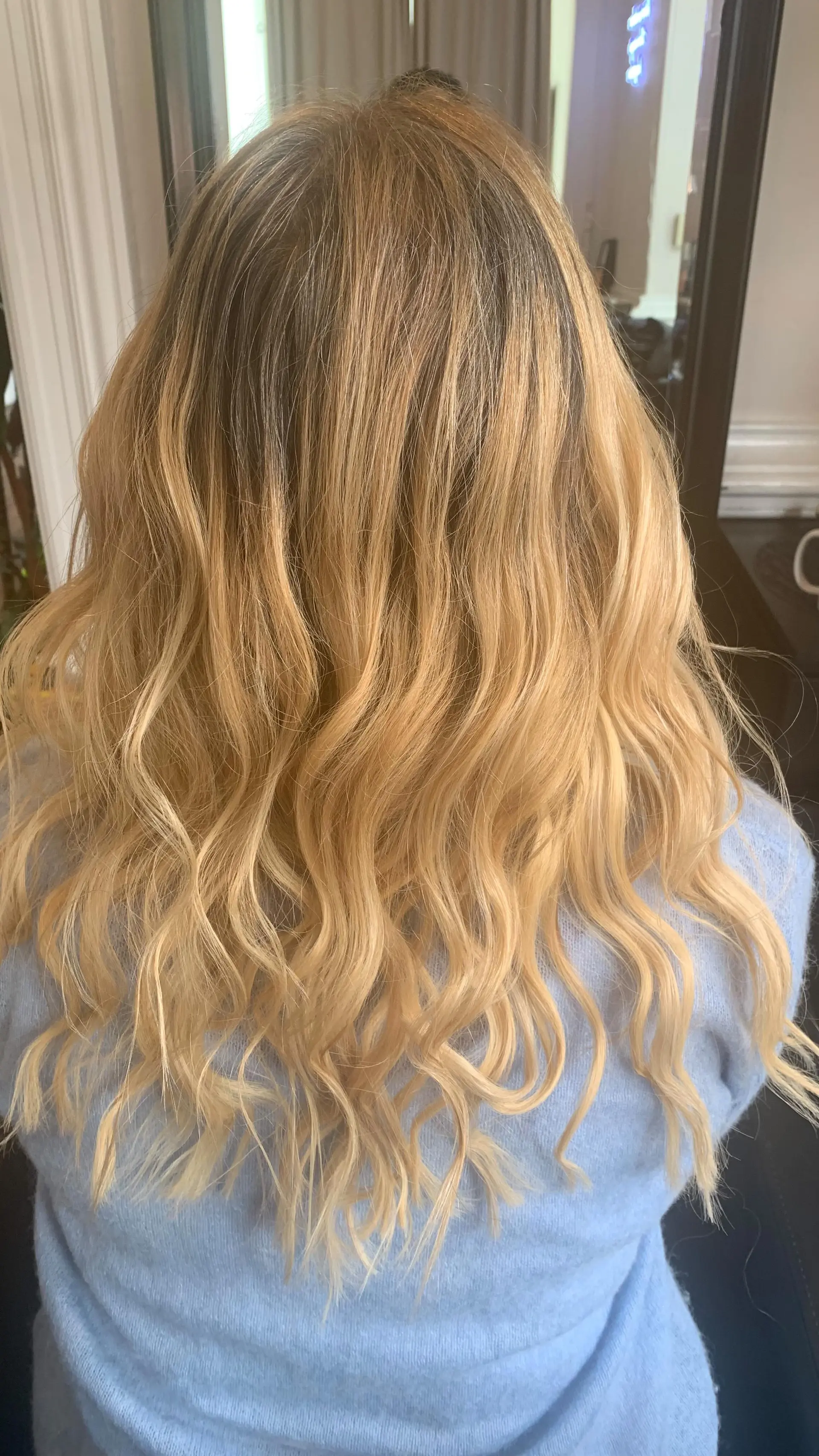 Long honey-golden blonde hair enhanced with extensions and styled into relaxed, textured waves. 1