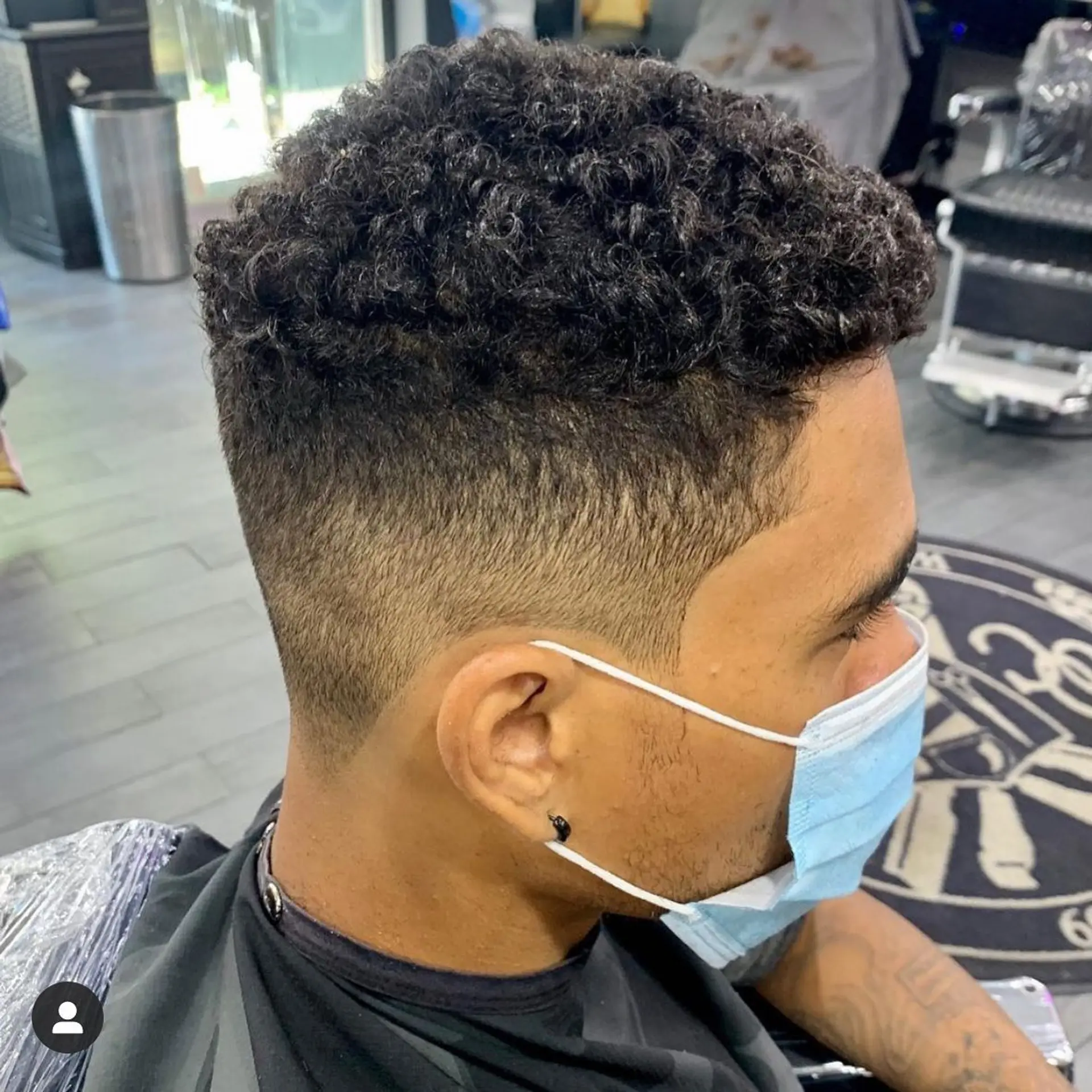 A clean mid fade haircut paired with natural textured curls on top. 1