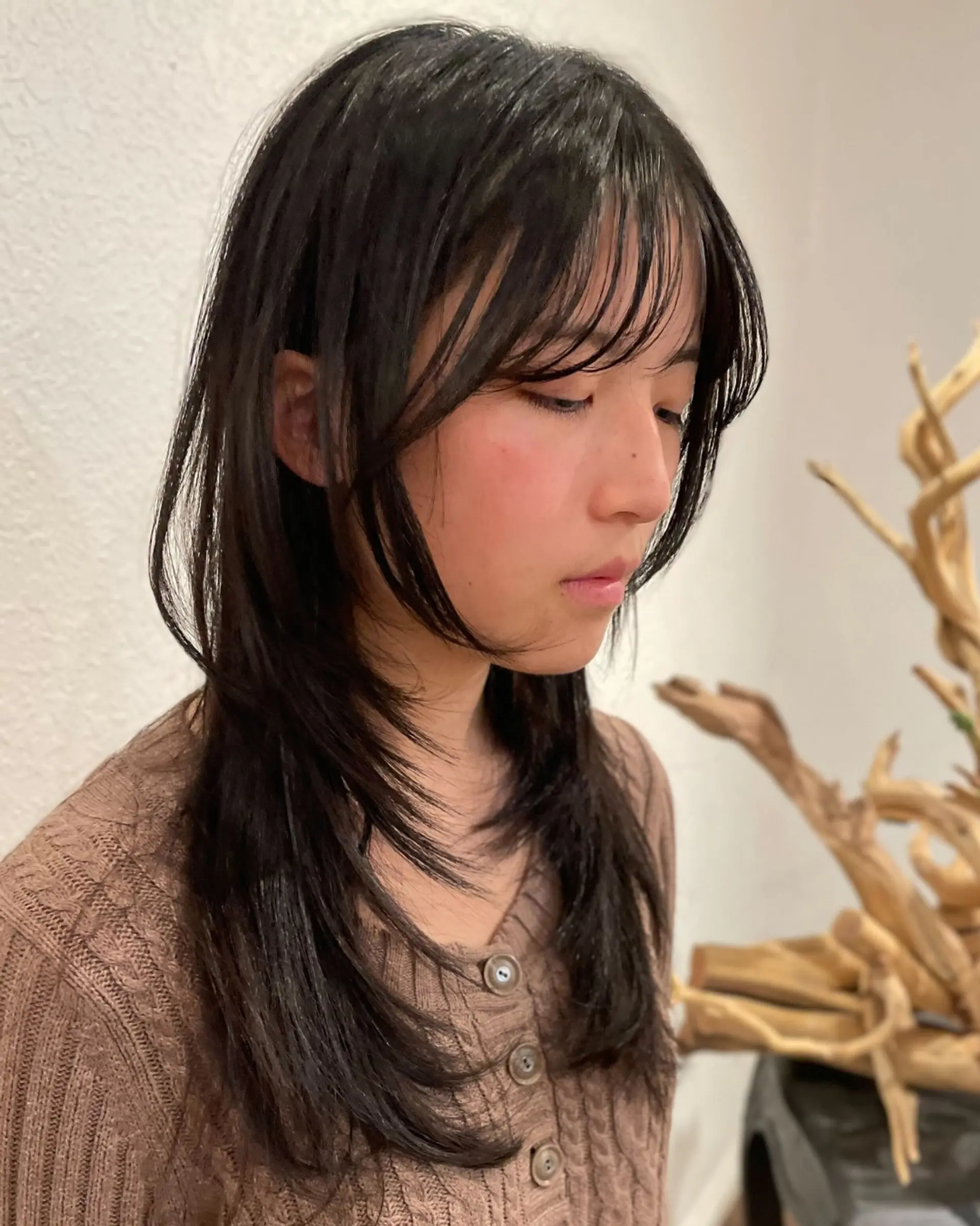 Long straight dark hair cut with soft face-framing layers and airy, wispy bangs. 1