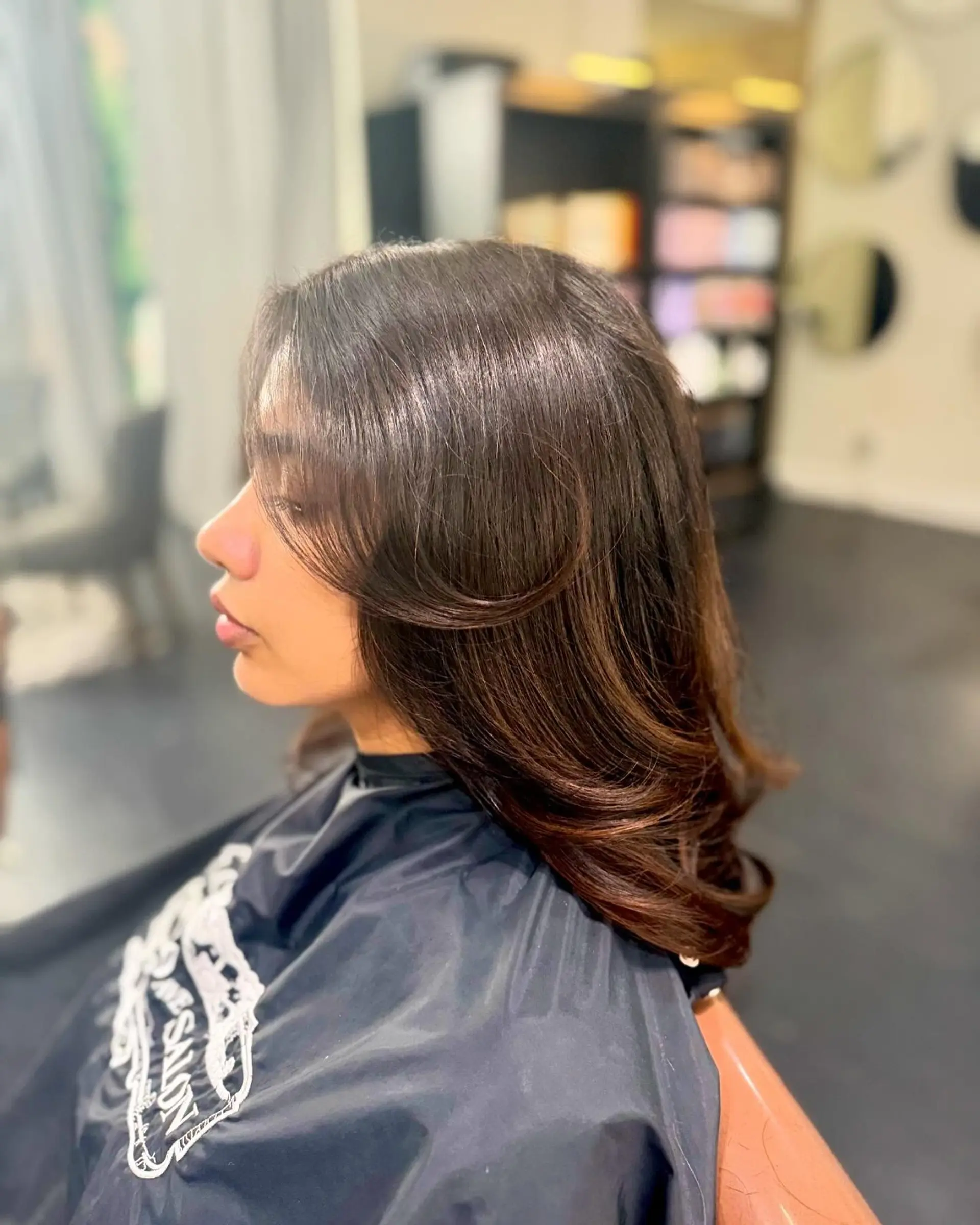 Glossy, medium-length dark brown hair styled with soft face-framing layers, curtain bangs, and smooth turned-under ends. 1