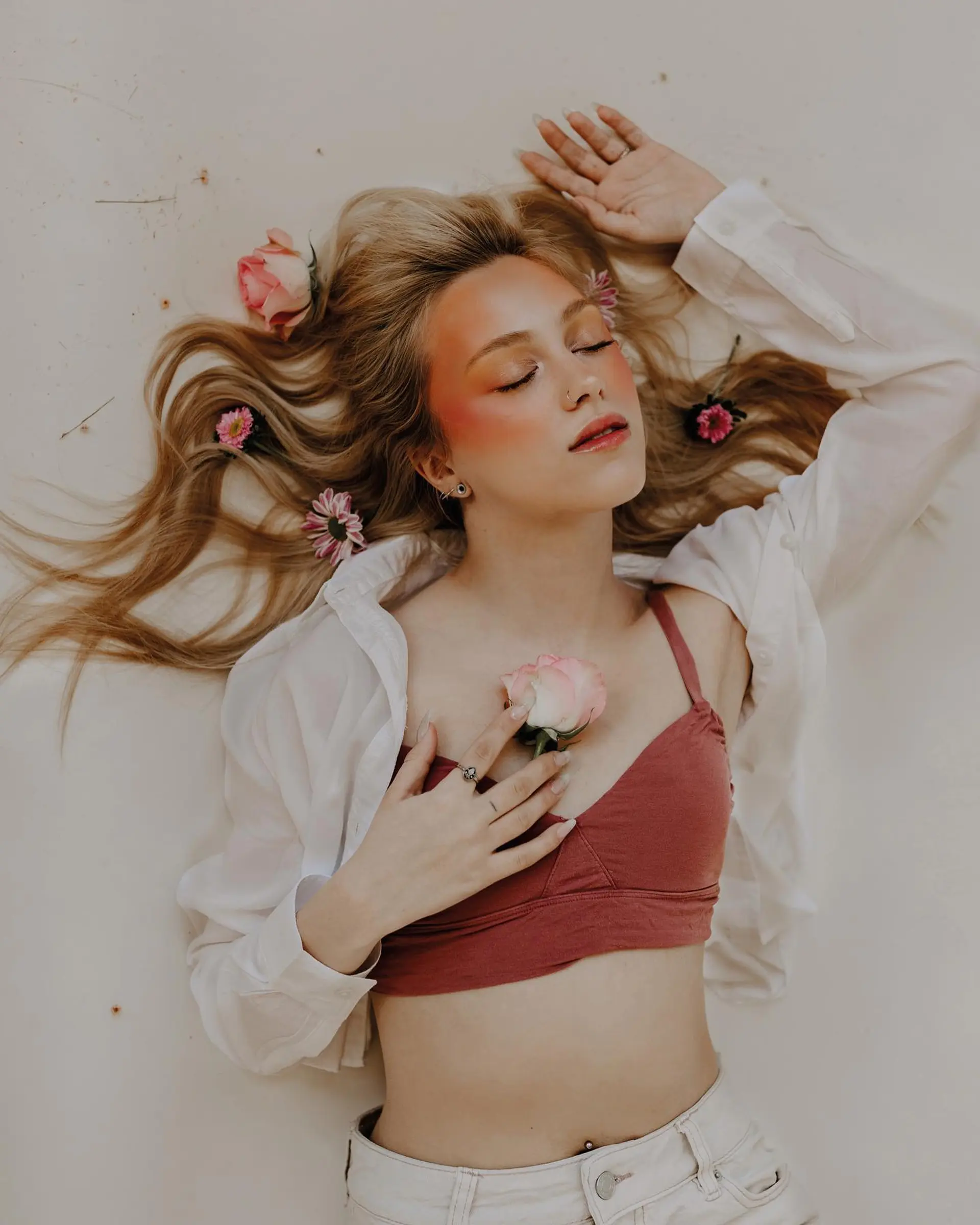 Long golden blonde hair styled into soft, natural waves spread gracefully with delicate floral accents. 1