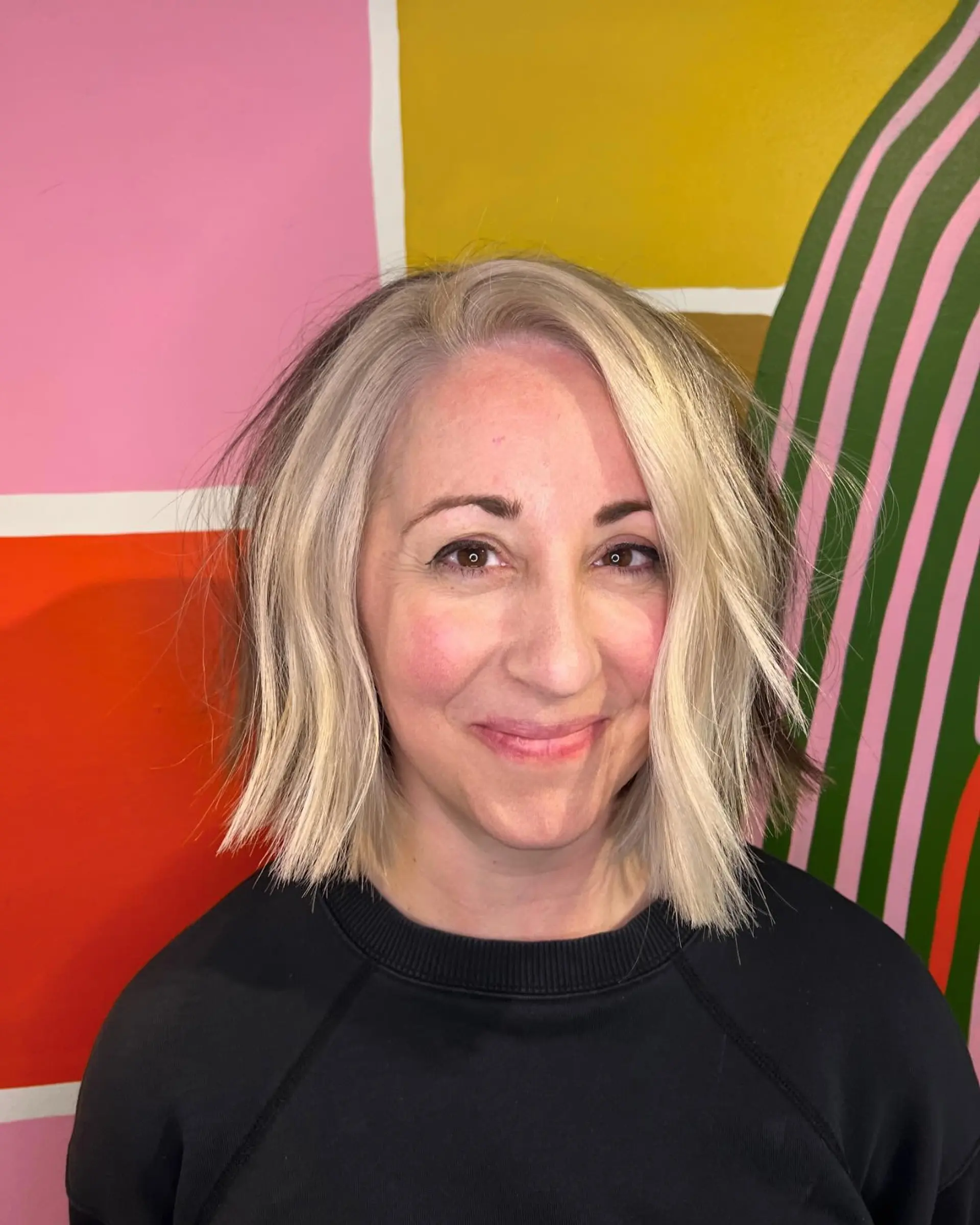 A modern chin-length textured bob cut featuring blunt, piecey ends and cool platinum blonde tones with a subtle tousled wave. 1