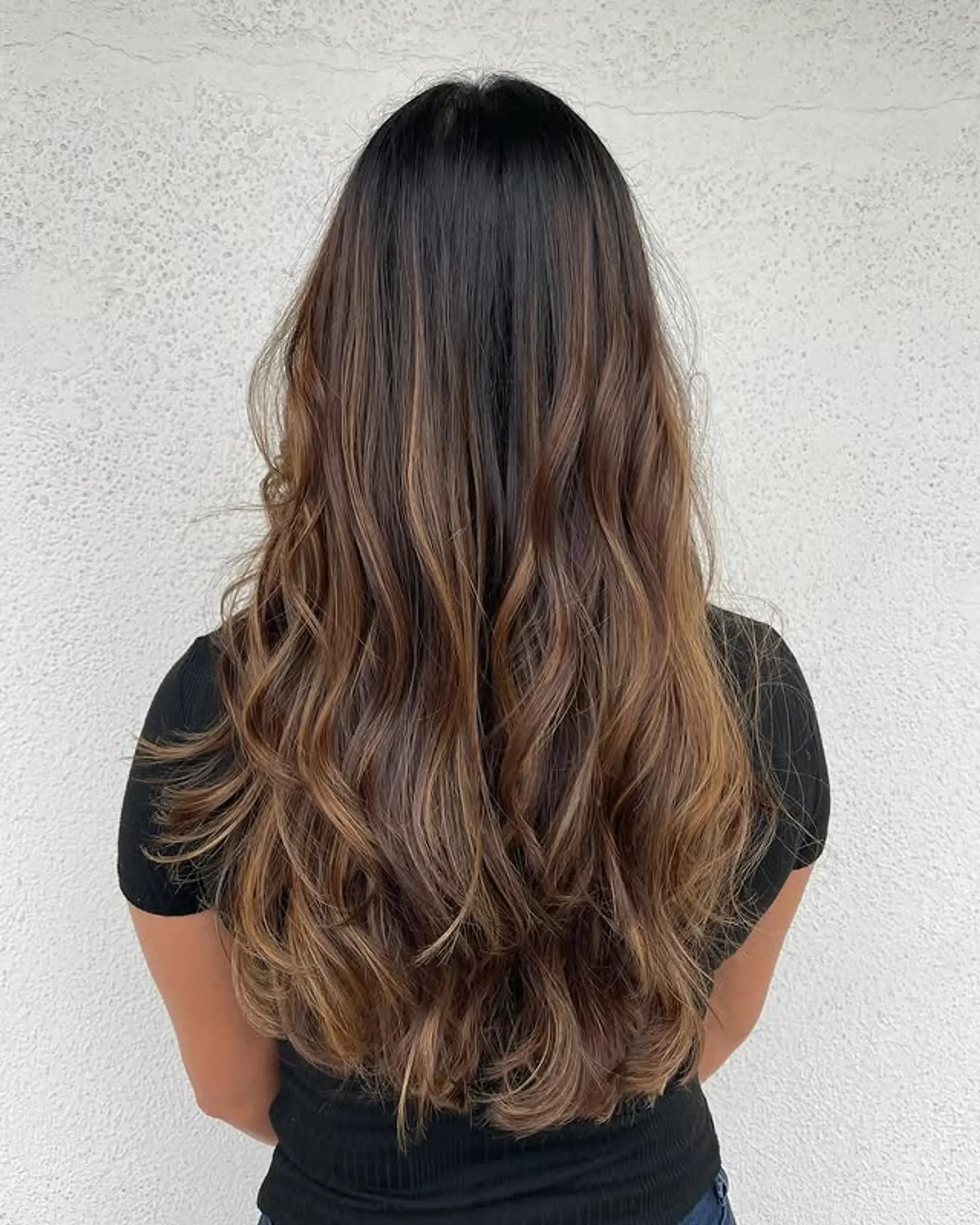 Long, layered wavy hair with a caramel swirl balayage. 1