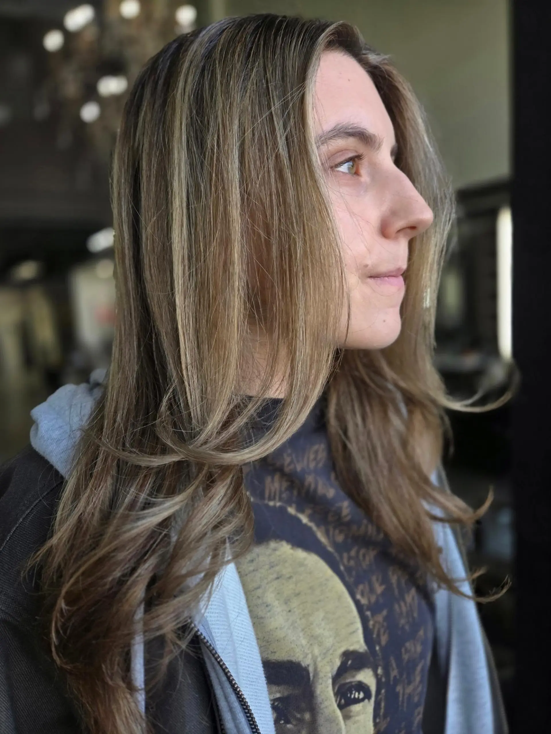 Long light brown hair featuring soft, blended honey blonde highlights and face-framing layers with gently curled ends. 1