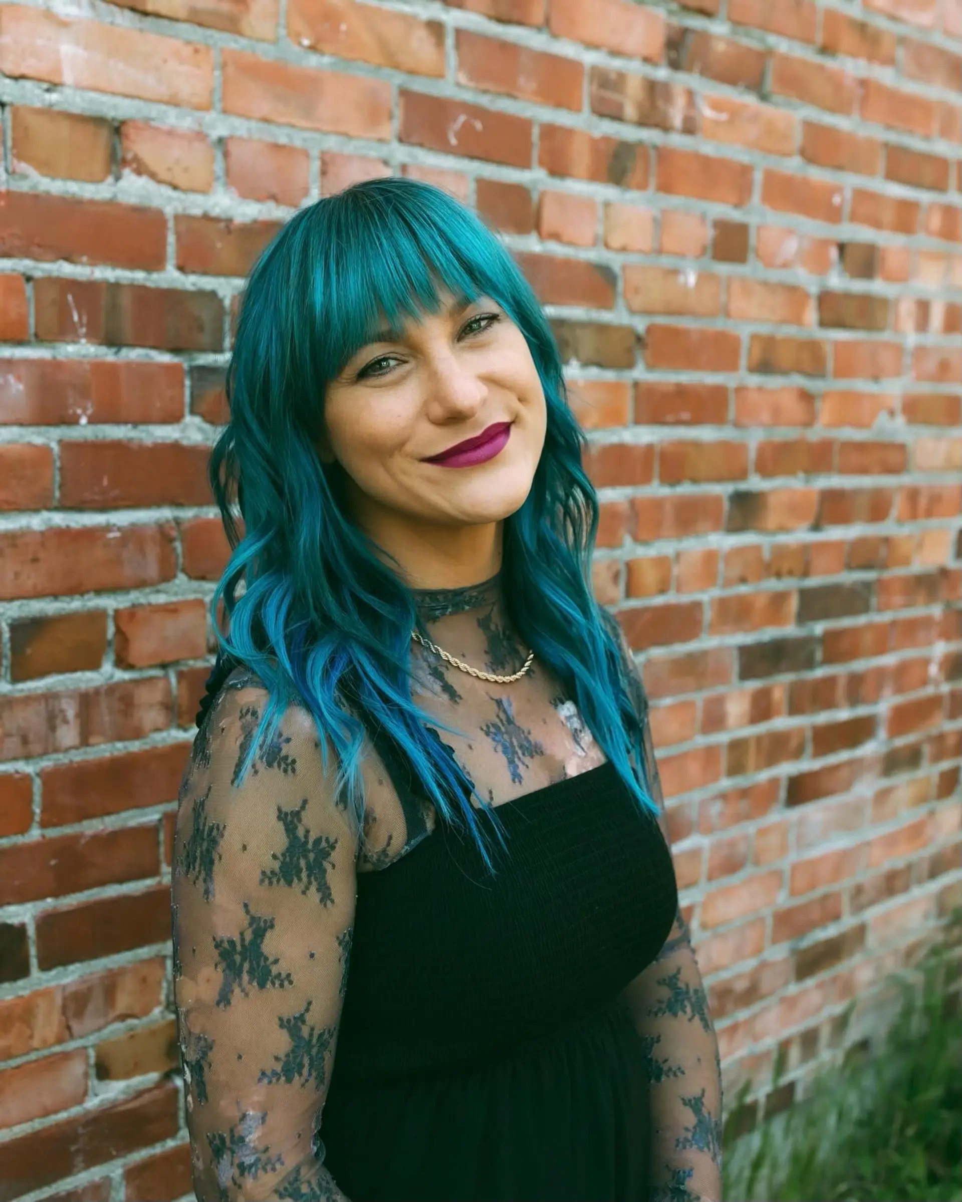 Vibrant teal medium-length hair styled in loose beach waves with a straight-across, piecey full fringe. 1