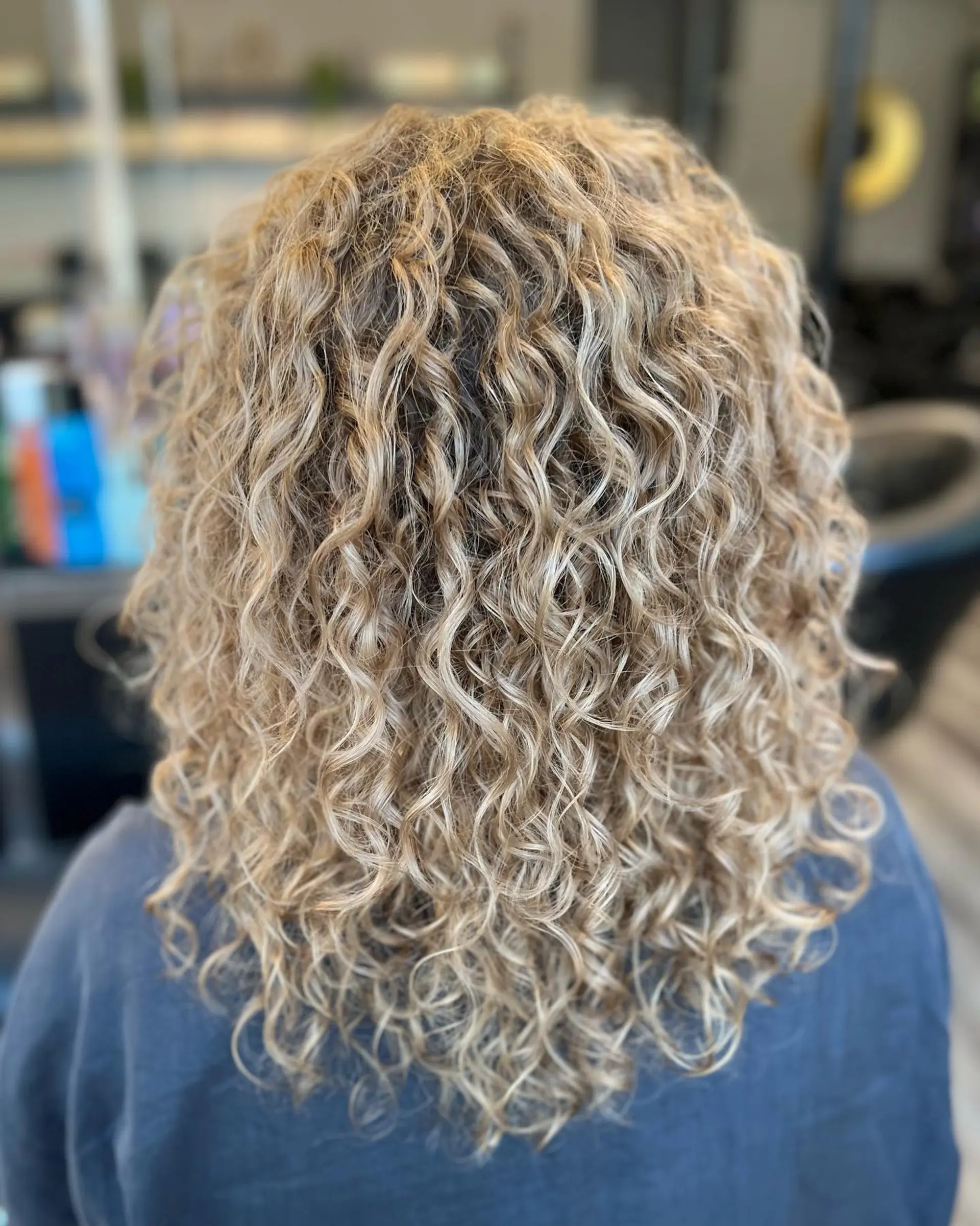 A medium-length curly perm with defined curls for a voluminous look. 1