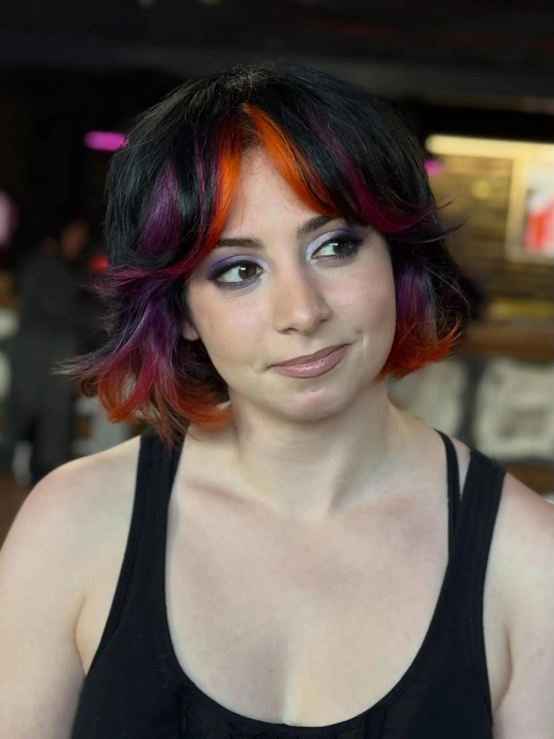 A short, textured shag bob featuring flared ends, center-parted curtain bangs, and bright orange and purple vivid color blocks against a dark base. 1