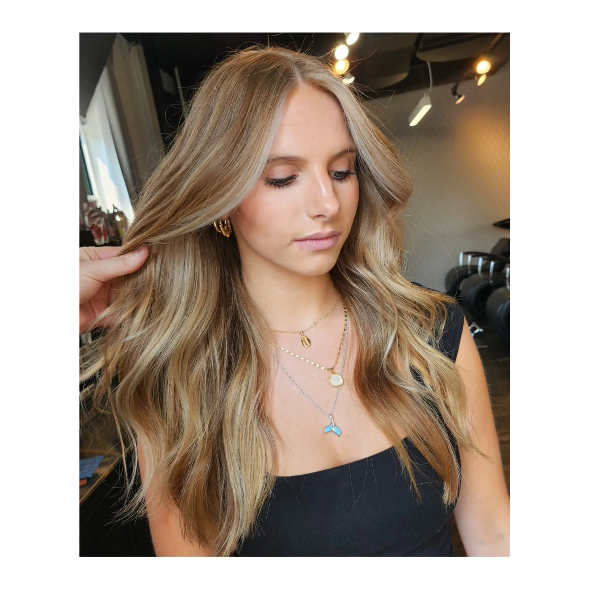 Long dimensional blonde hair featuring a blended balayage color melt styled into soft, natural waves. 1