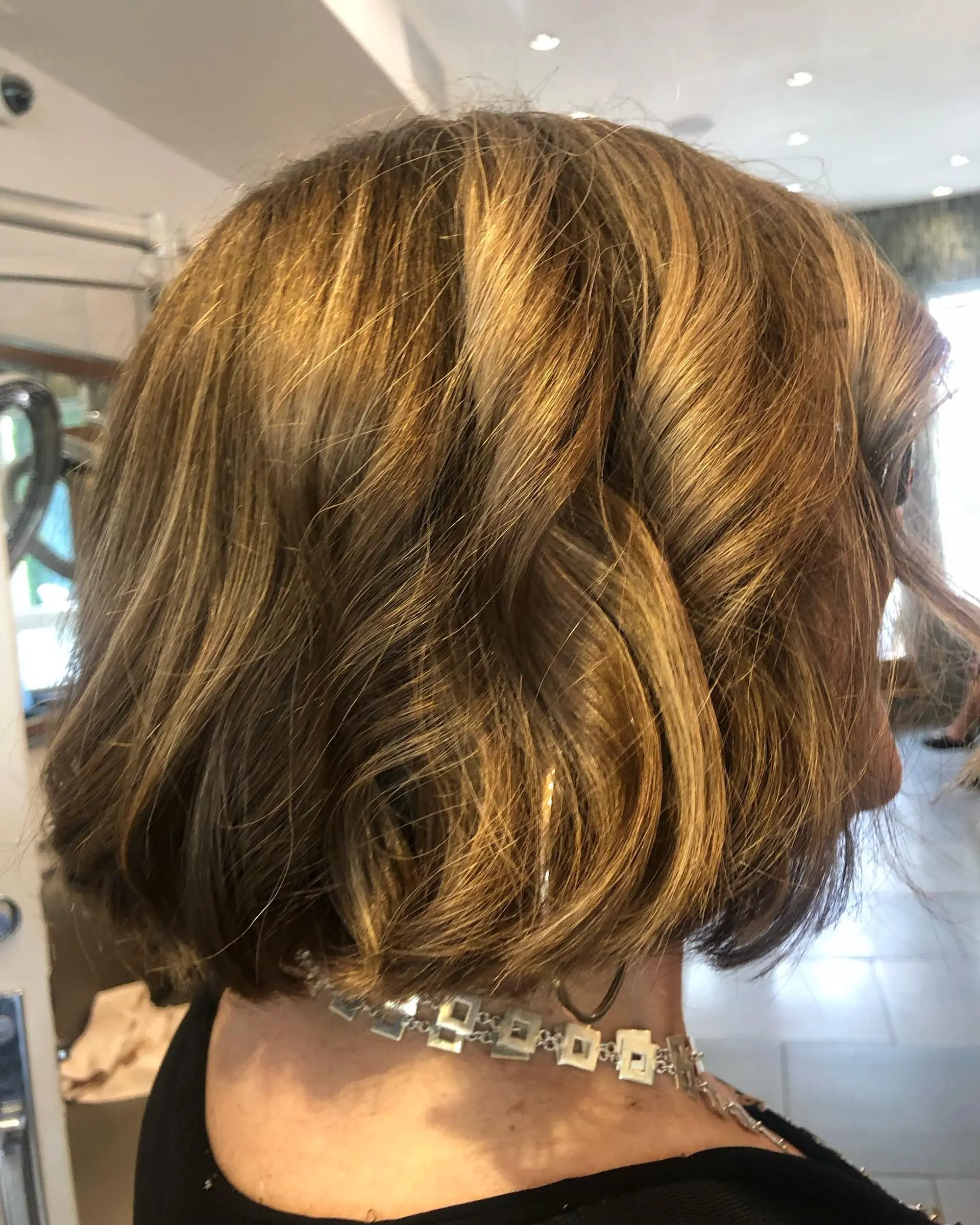 A neck-length bob styled with soft waves and finished in a dimensional golden brown glaze. 1