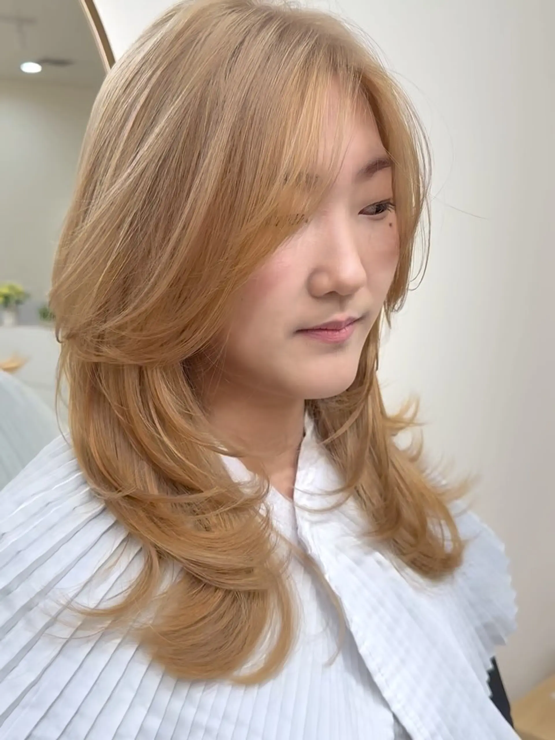 Medium-length warm golden blonde hair styled in soft, bouncy face-framing layers with gently flipped ends. 1