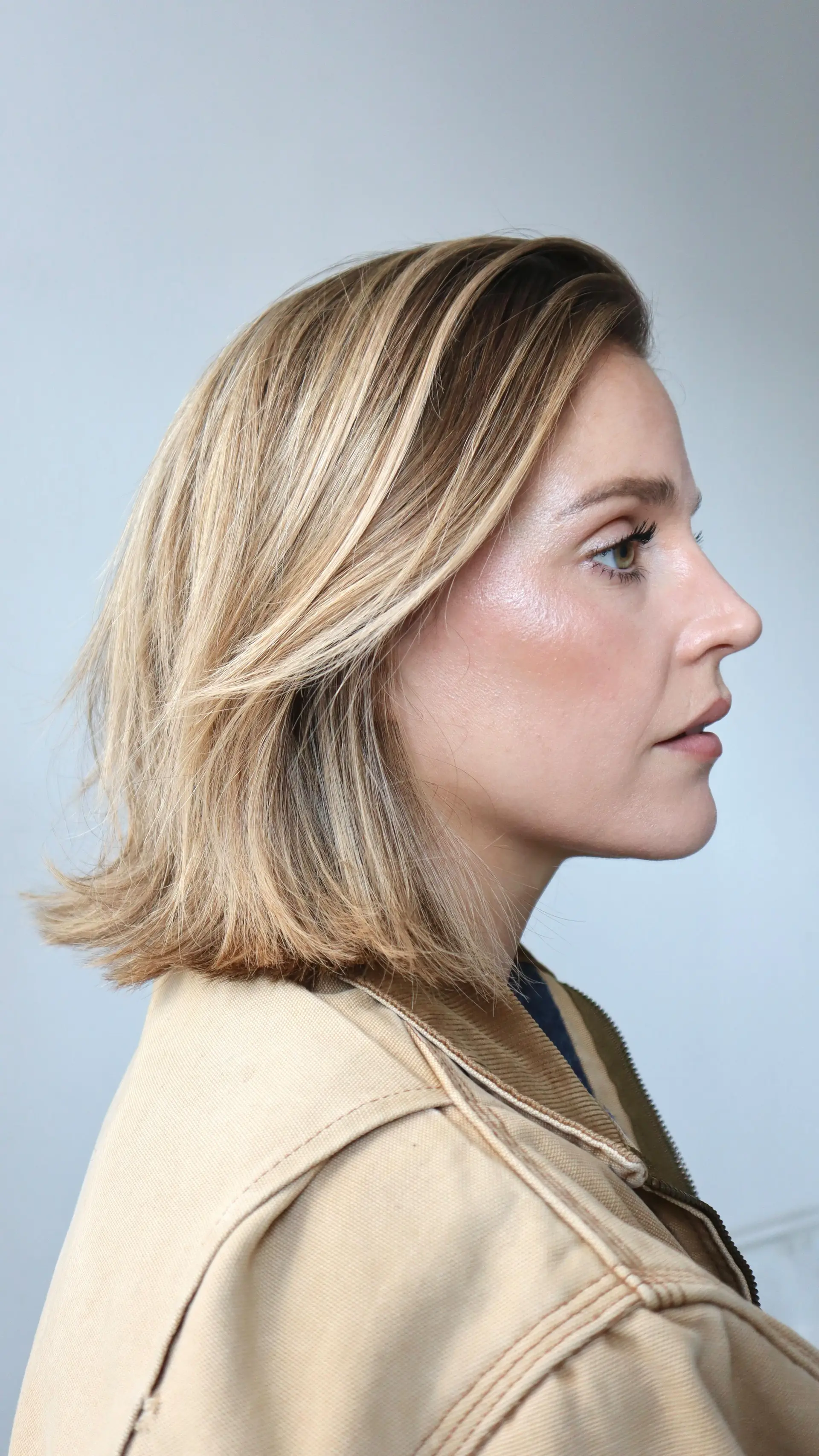 A textured, shoulder-skimming lob haircut featuring dimensional warm blonde highlights and soft face-framing layers. 1