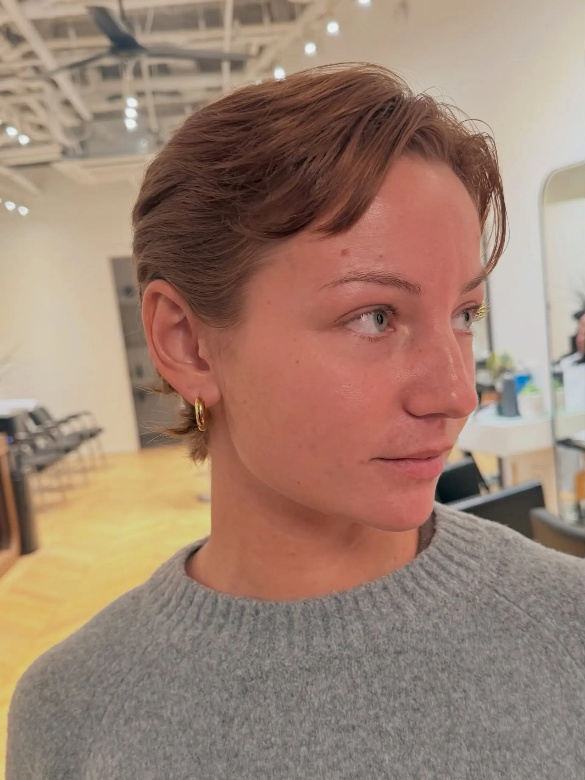 A soft copper pixie cut tucked behind the ear with subtle texture. 1