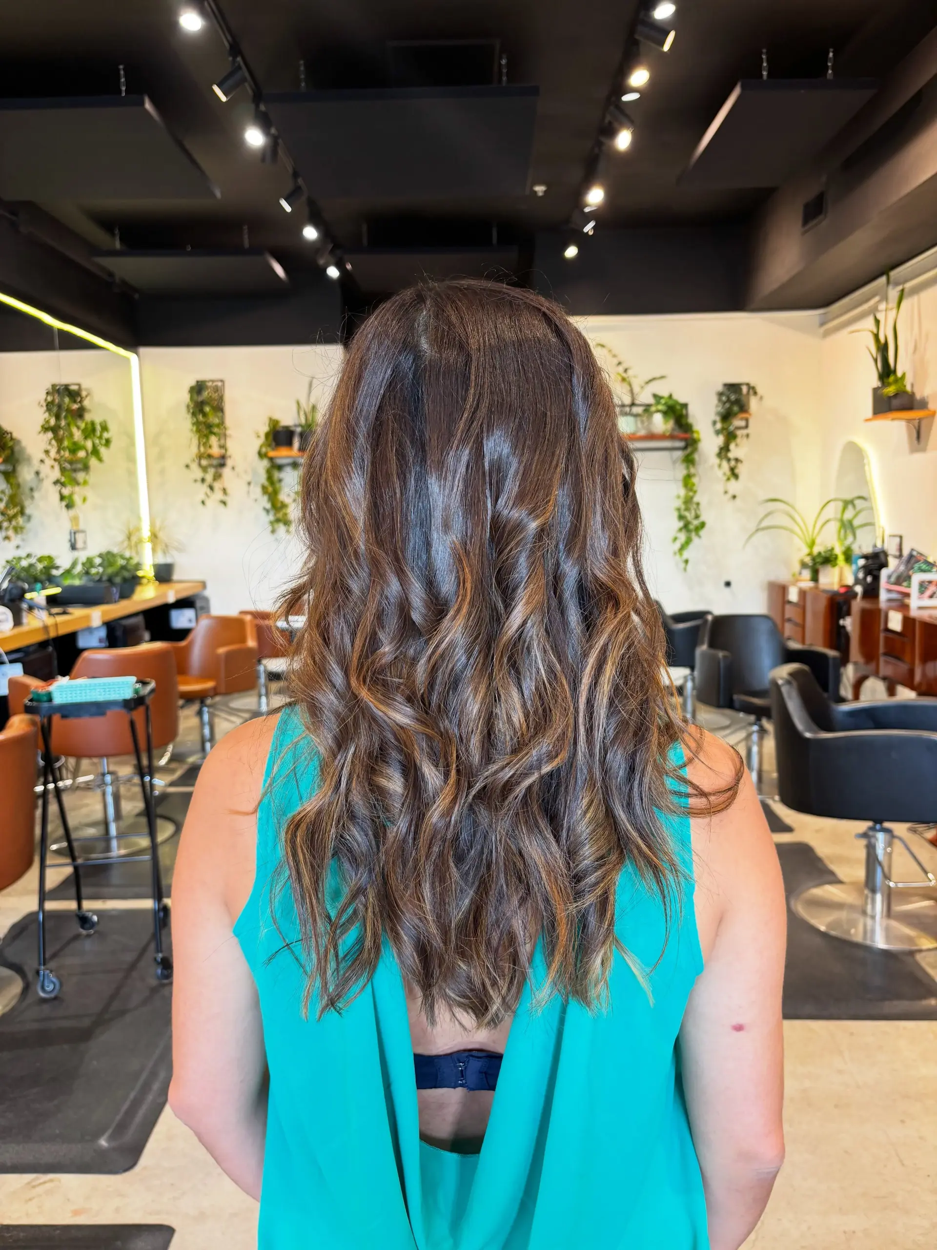 Long dimensional dark brunette hair with soft caramel balayage highlights styled in relaxed, glossy waves. 1