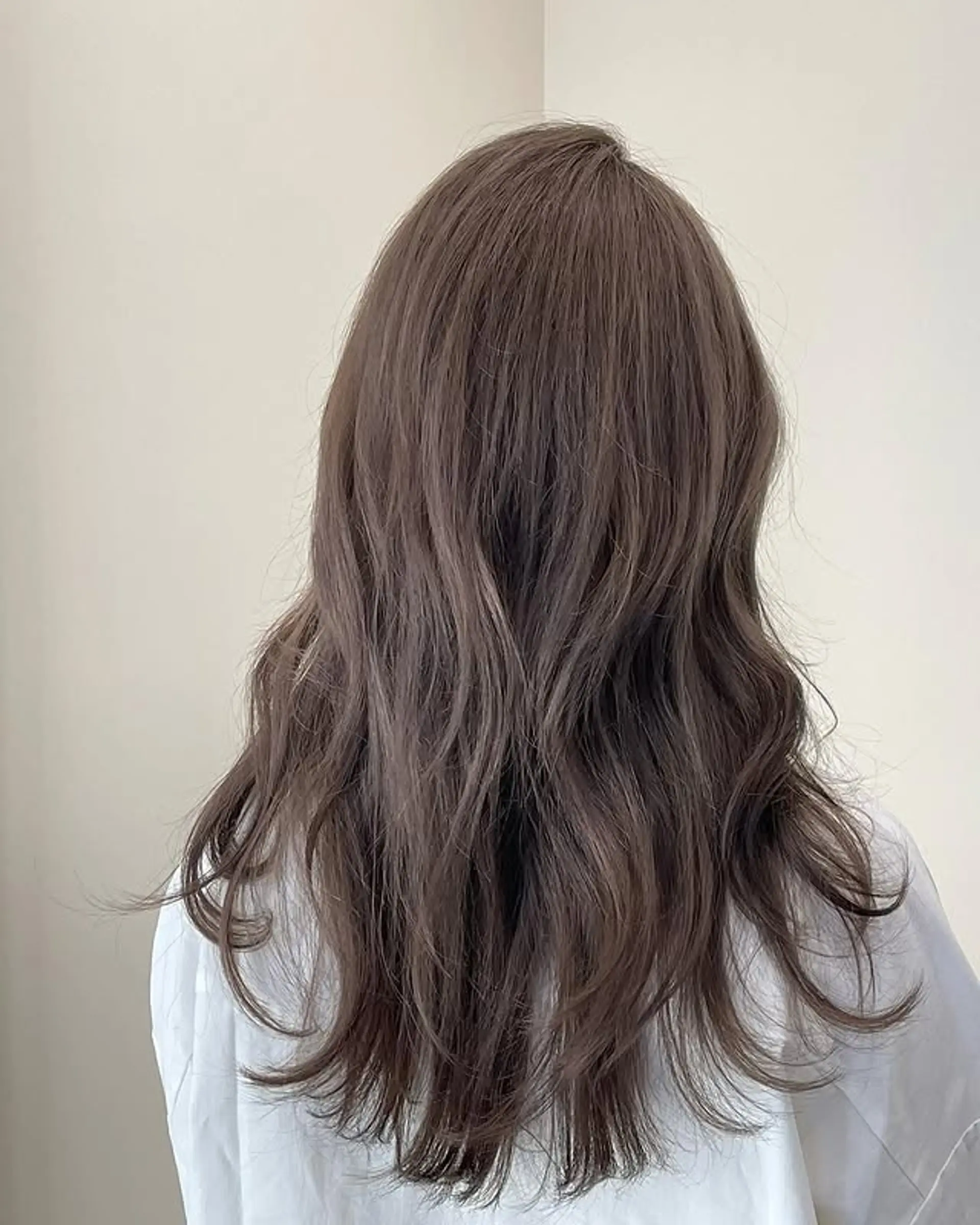 Long layered hair with subtle waves in an ash brown tone. 1