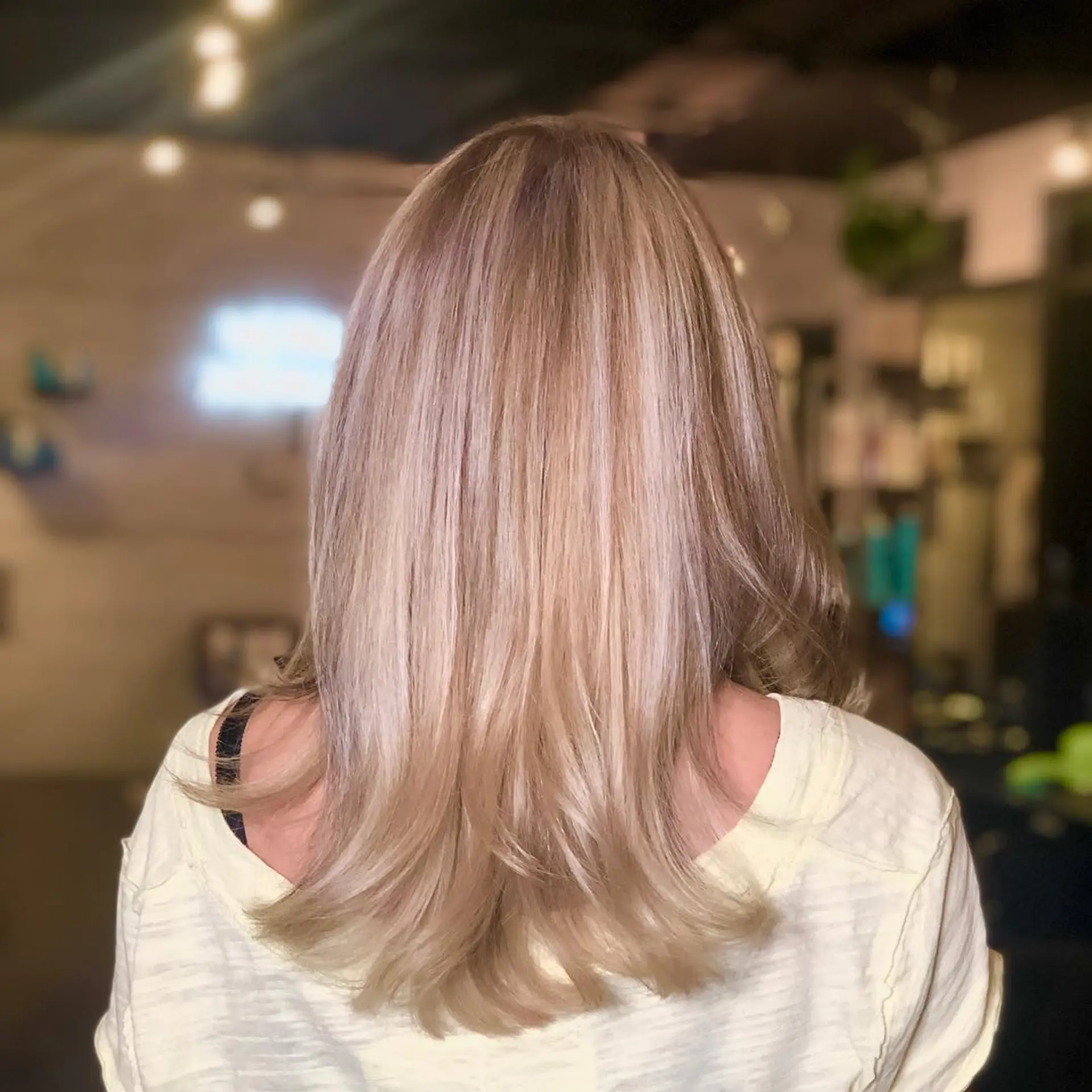 Medium-length dimensional blonde hair with fine highlights, styled straight with soft outward curls at the ends. 1