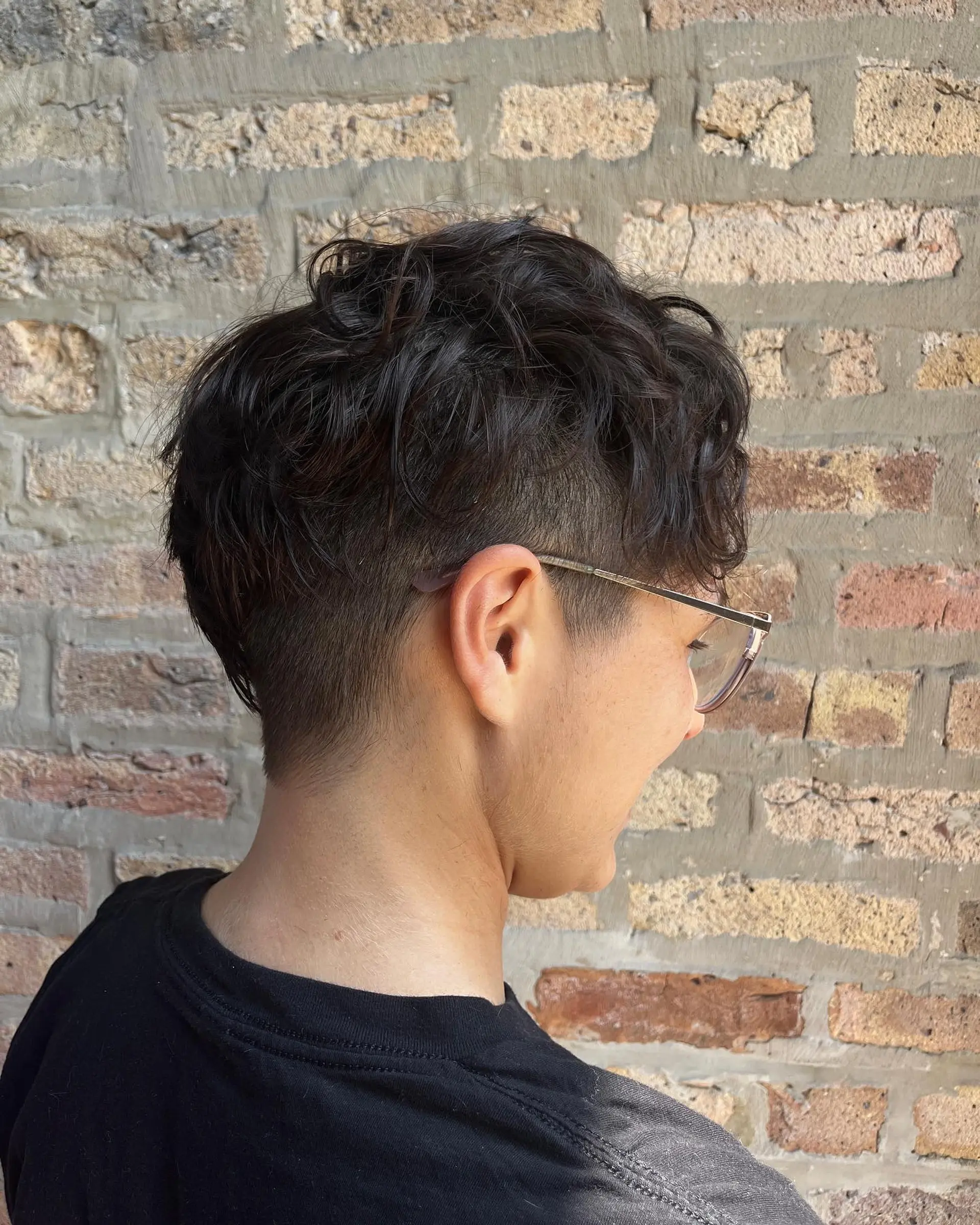 A short, textured crop with a taper fade, styled to enhance natural waves. 2