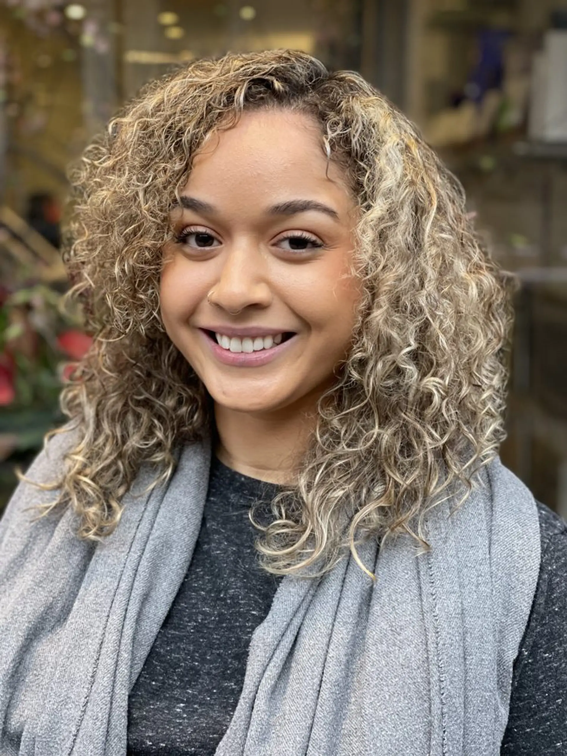 A medium-length curly hairstyle with blonde highlights and natural-looking curls, providing a voluminous and soft look. 1