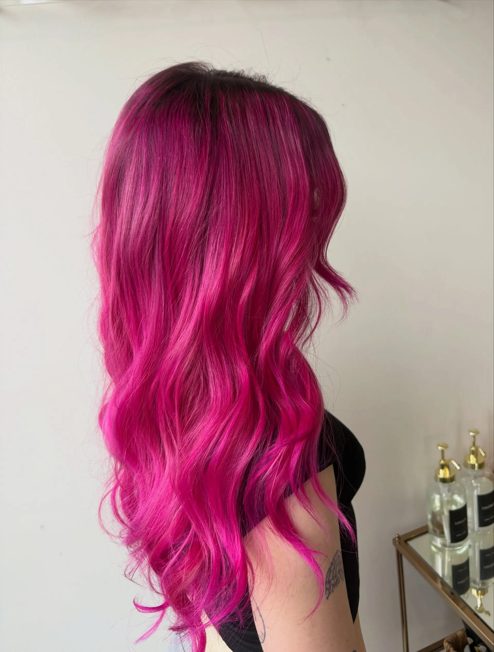 Vibrant magenta-pink hair with dark roots, styled into soft cascading waves. 1
