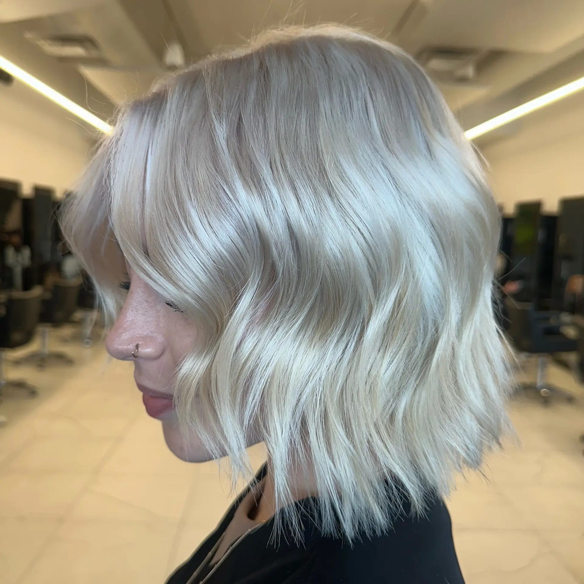A textured, chin-to-neck length bob in an ultra-cool icy platinum blonde shade, styled with loose, relaxed waves. 1