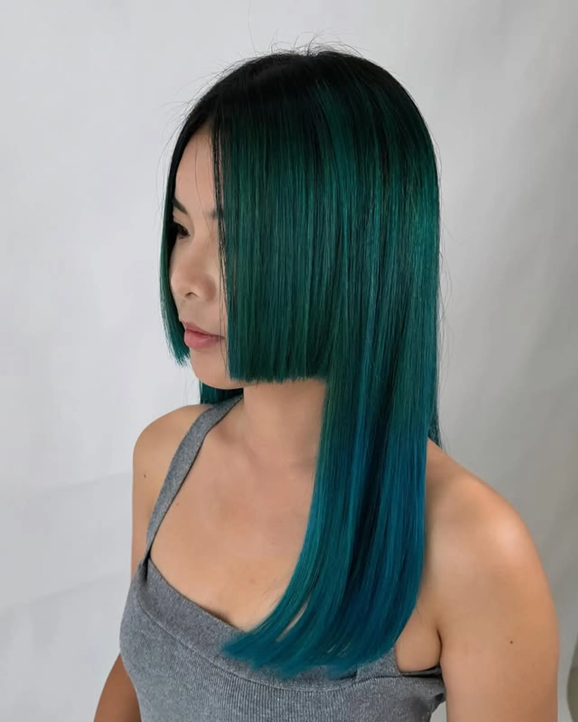 A blunt bob with a dark root that transitions into vibrant emerald green and teal ombre ends. 1